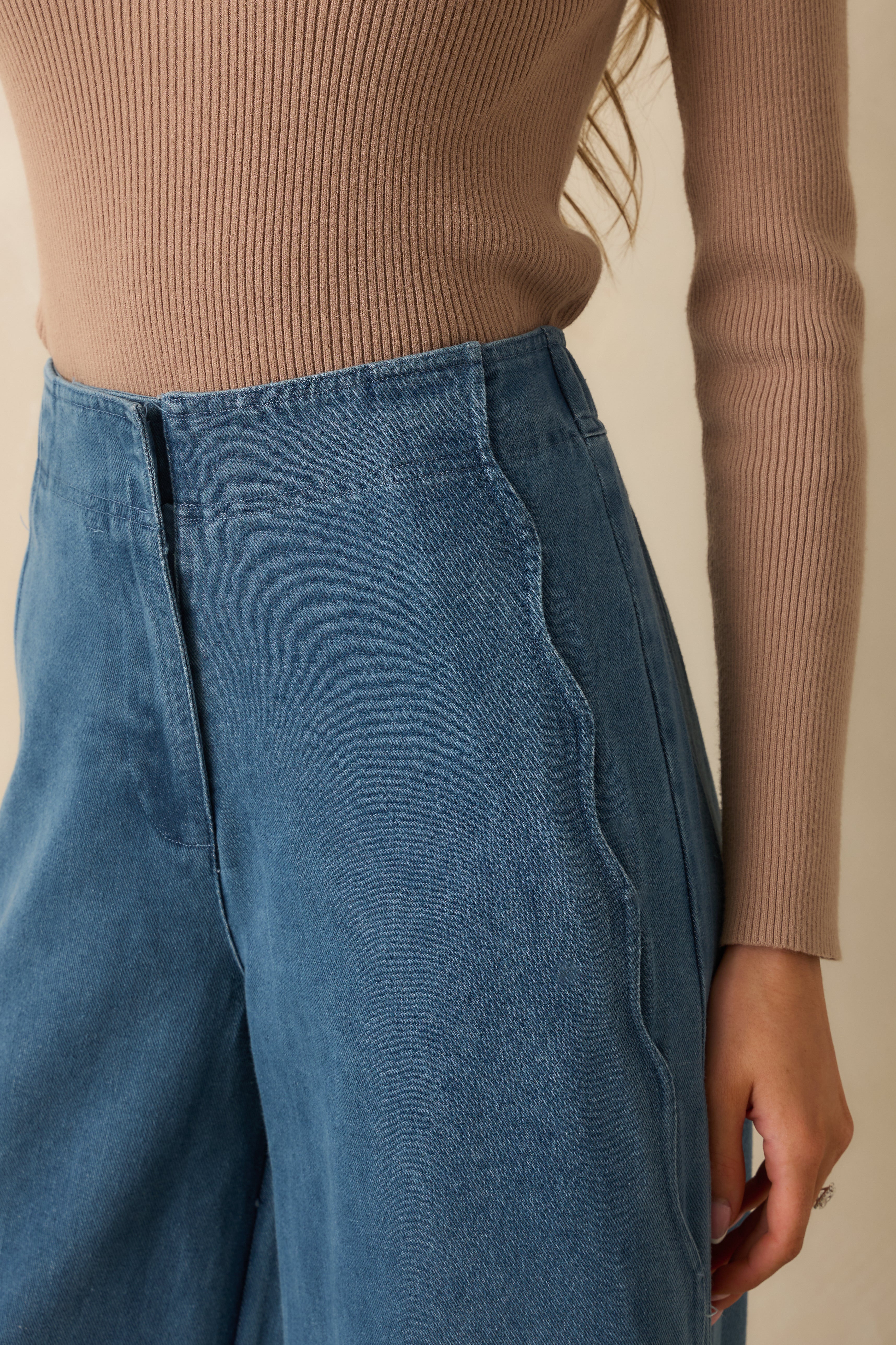 Close-up of the denim fabric and scalloped seam detail along the side of the jeans.