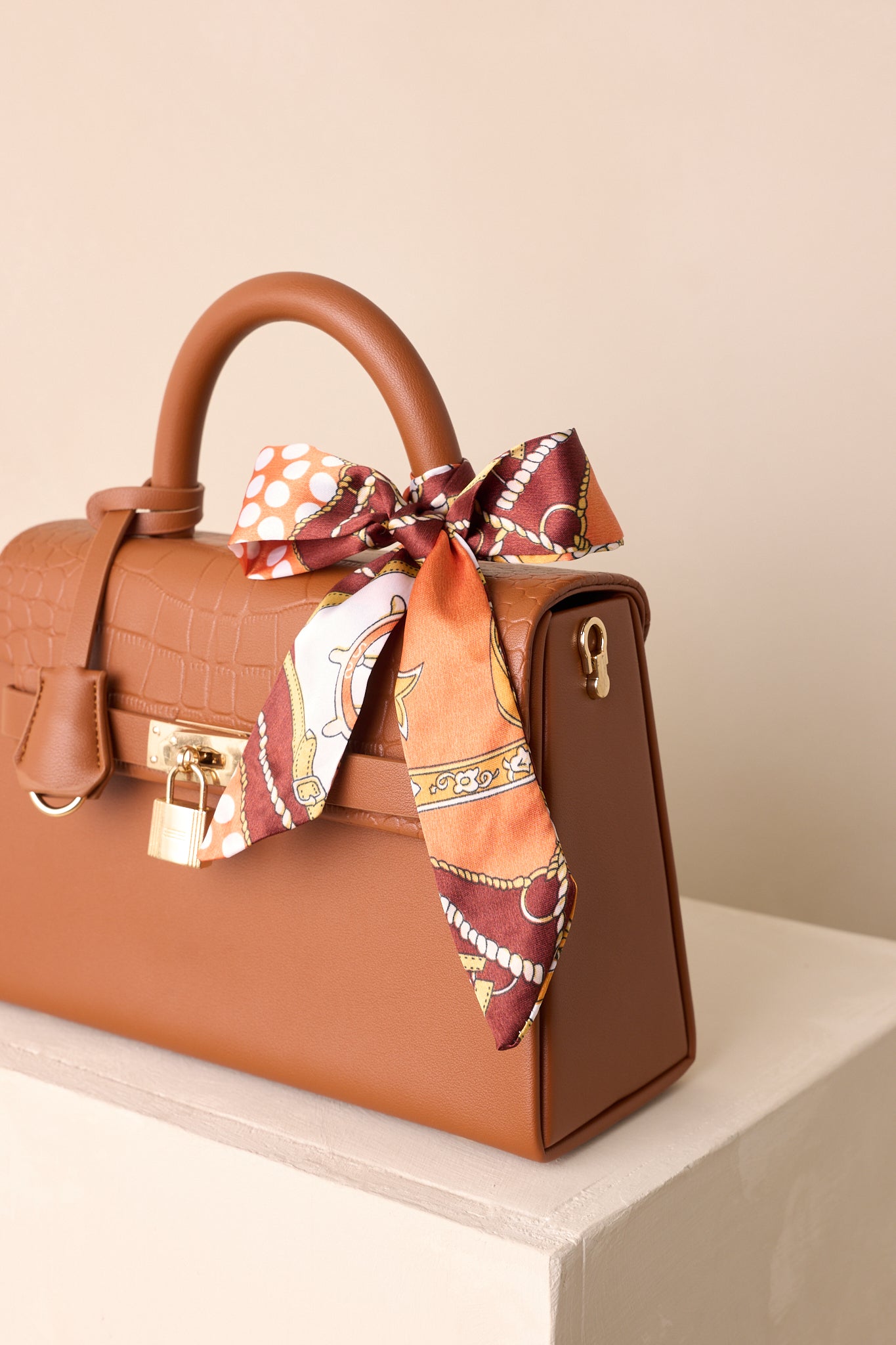 A close-up detail shot of the faux croc removable flap and functional padlock closure.