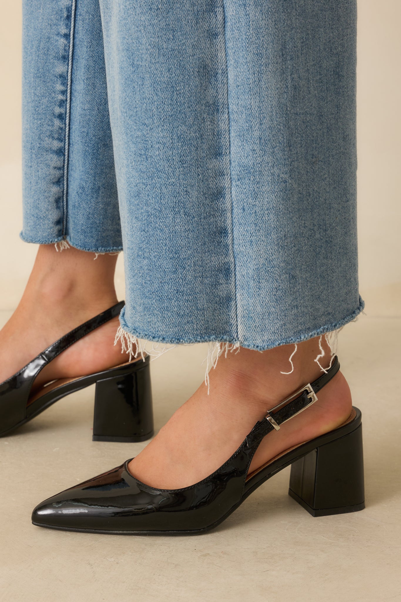Detail view capturing the high-shine patent finish and precise stitching along the pointed toe of the heel.