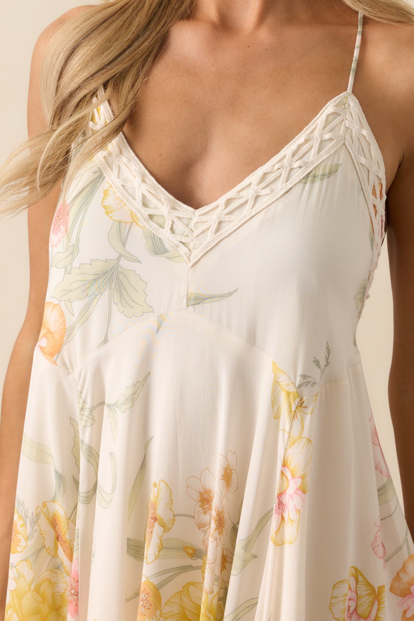 Close-up detail of the embroidered trim and multicolor floral print against the ivory fabric.