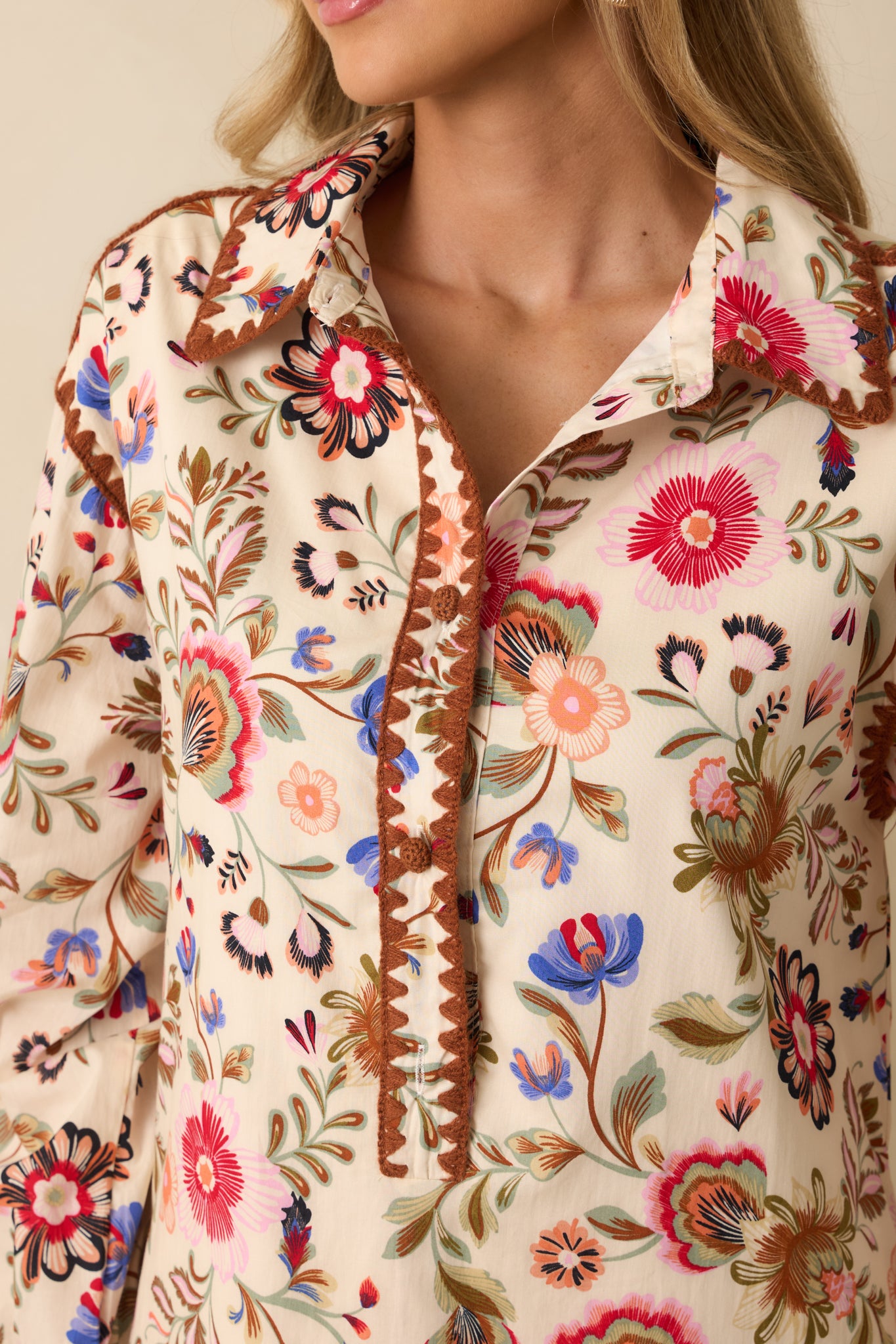 Close-up detail shot of the embroidered stitching and floral print on the ivory cotton fabric.