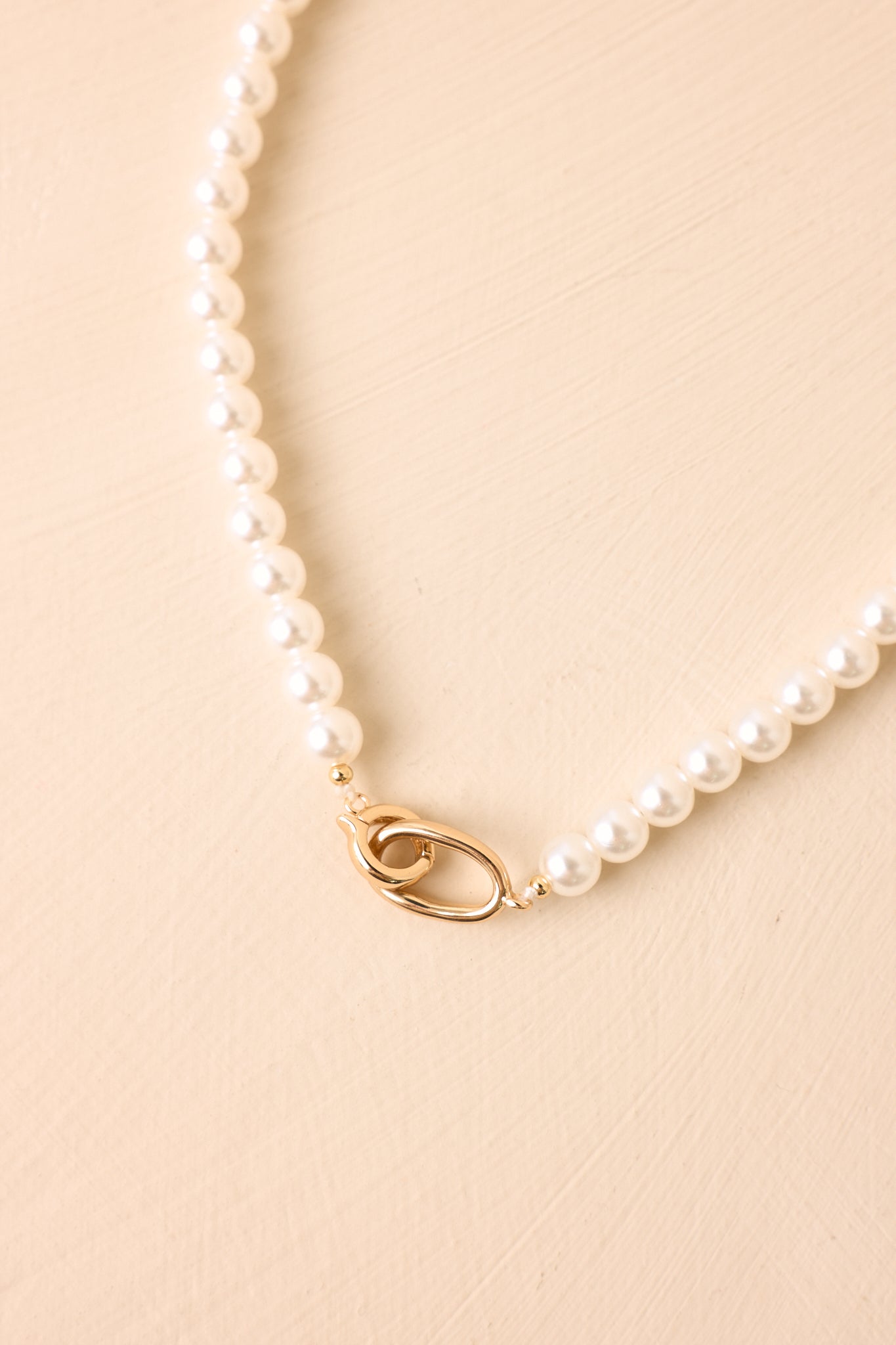 Close-up of the faux pearl necklace highlighting the smooth pearl finish, polished gold-tone hinged clasp, and convenient snap closure.