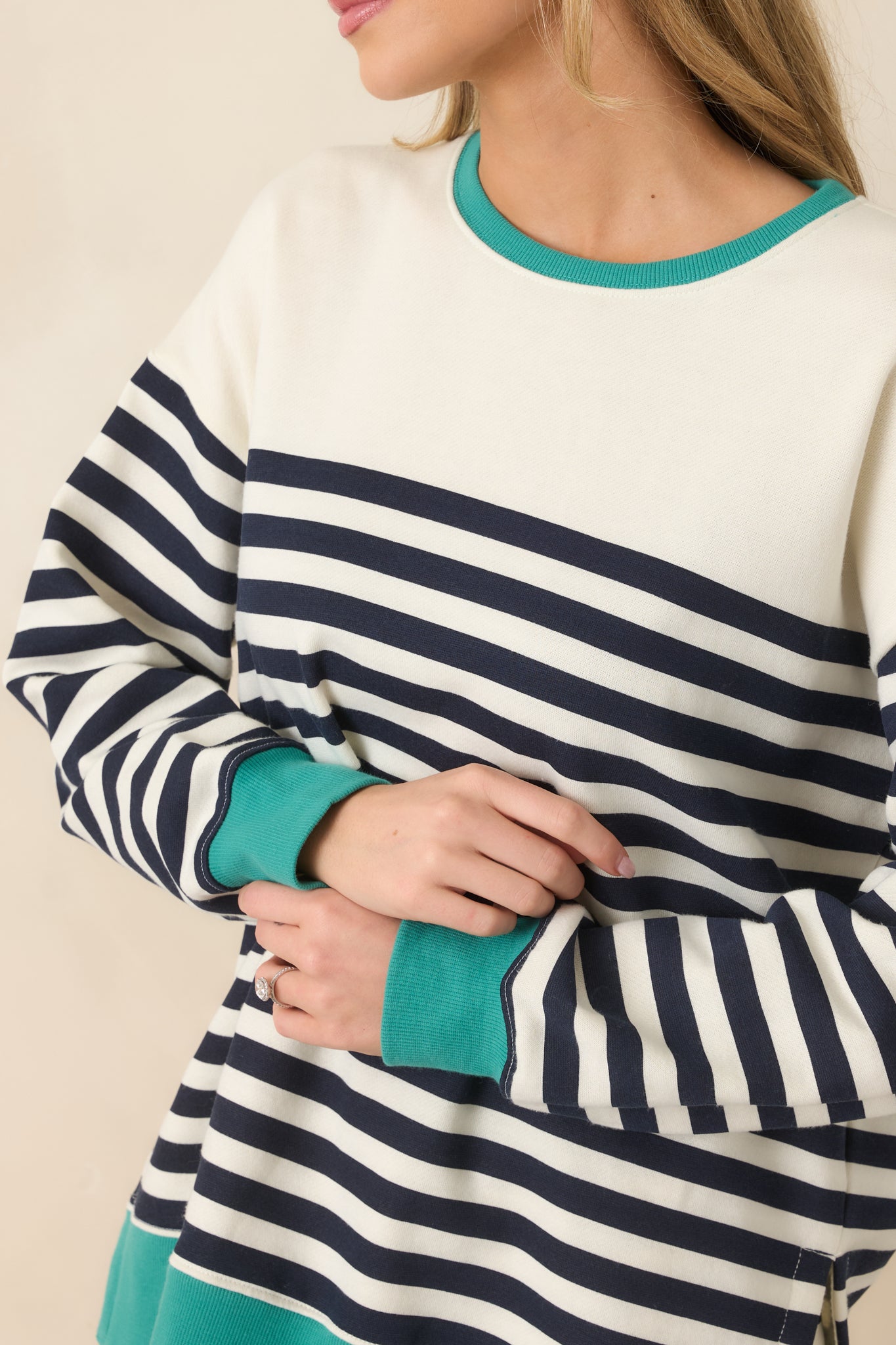 Close-up of cotton-blend fabric featuring navy and ivory stripes with textured teal ribbed trim and visible stitching.