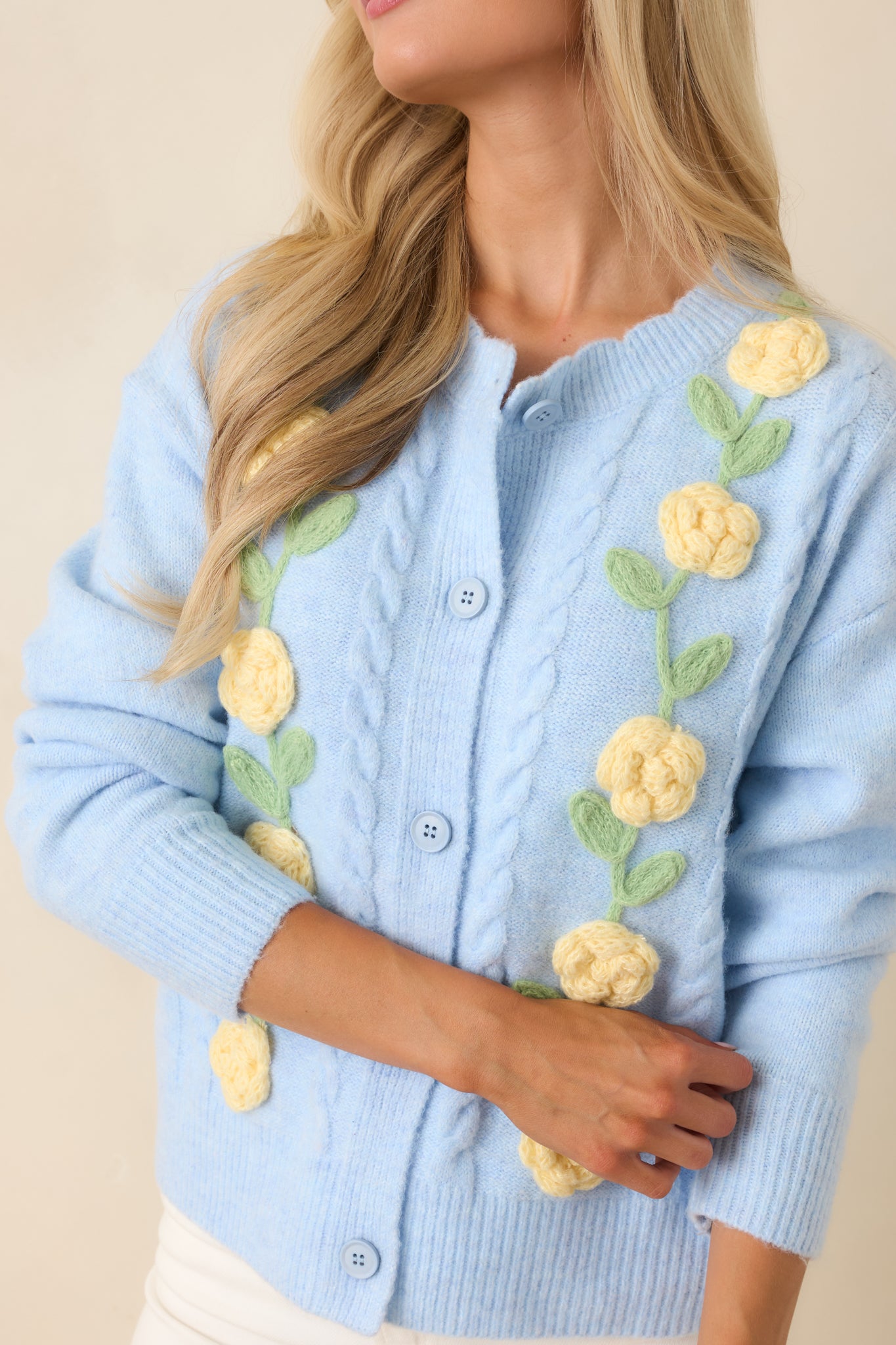 Close-up of the raised floral appliqué detailing, knit texture, and button-front design on the cardigan.