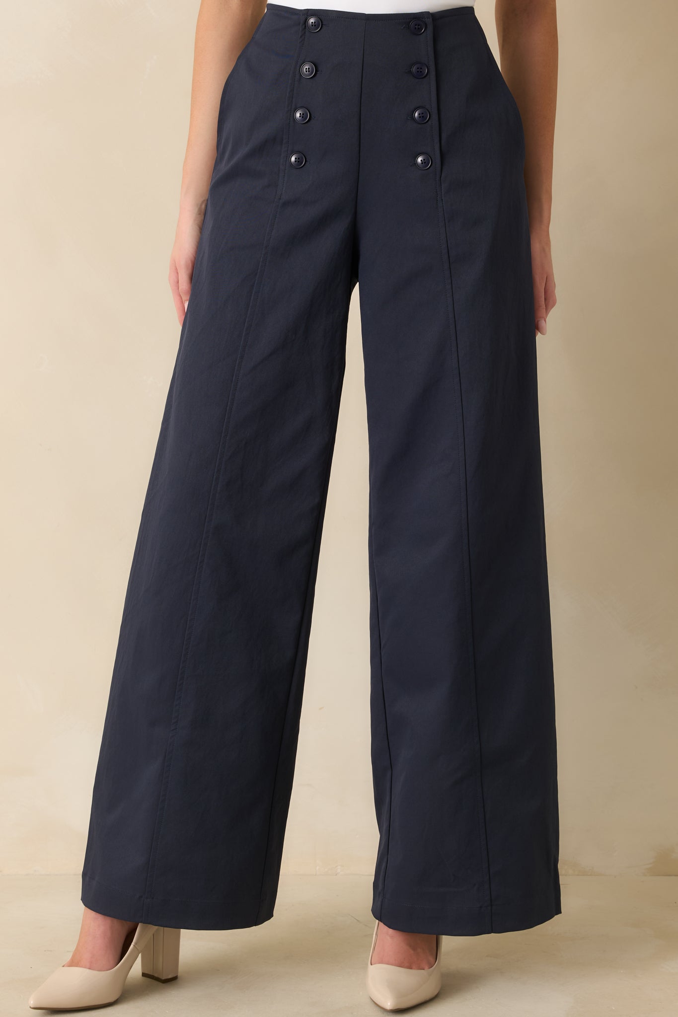Close-up of front pockets and buttoned waistband emphasizing the tailored, elongating fit of navy pants.