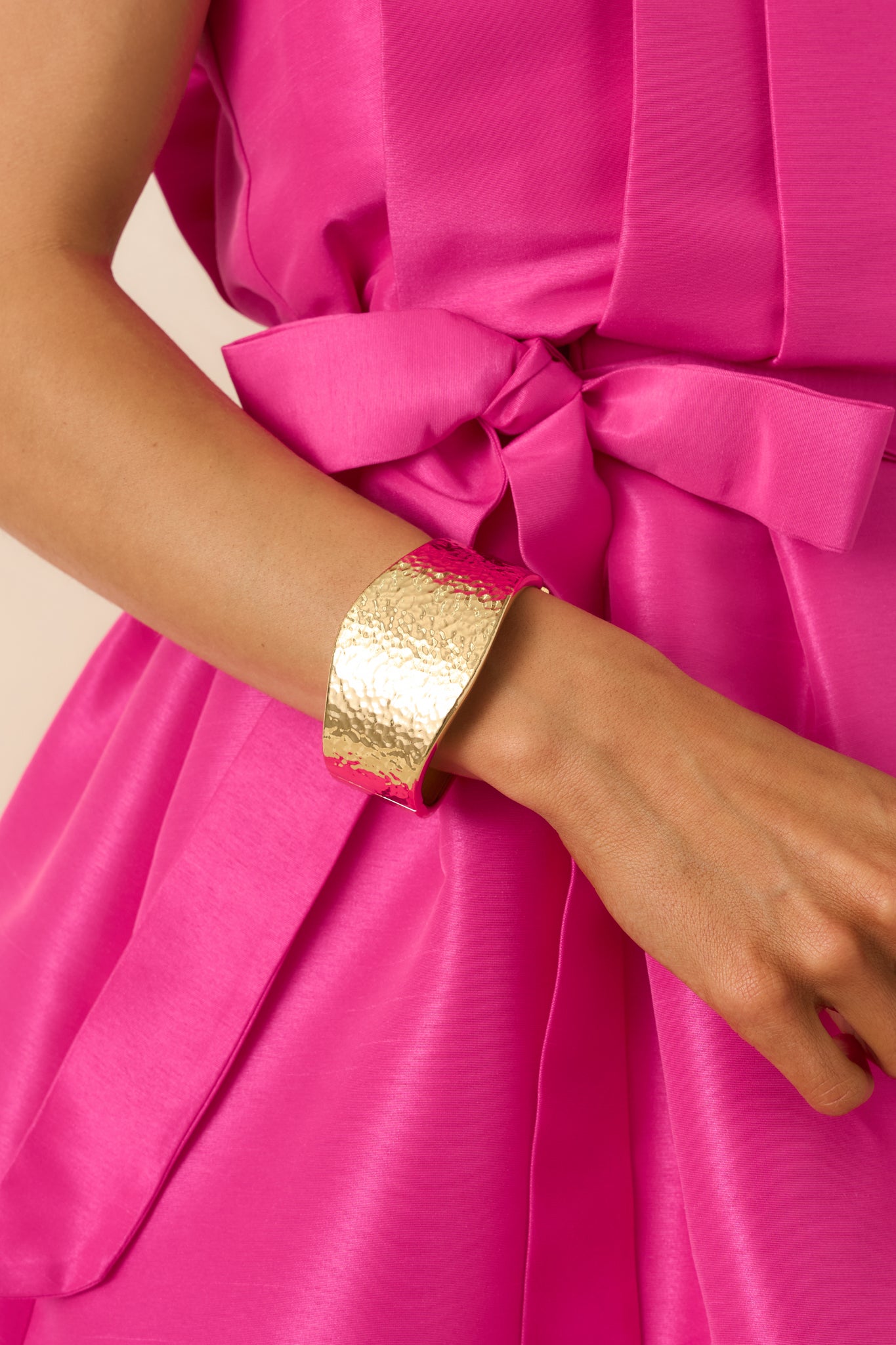 Detailed close-up of the gold-tone cuff bracelet focusing on the hammered texture, wide silhouette, and hinge closure.