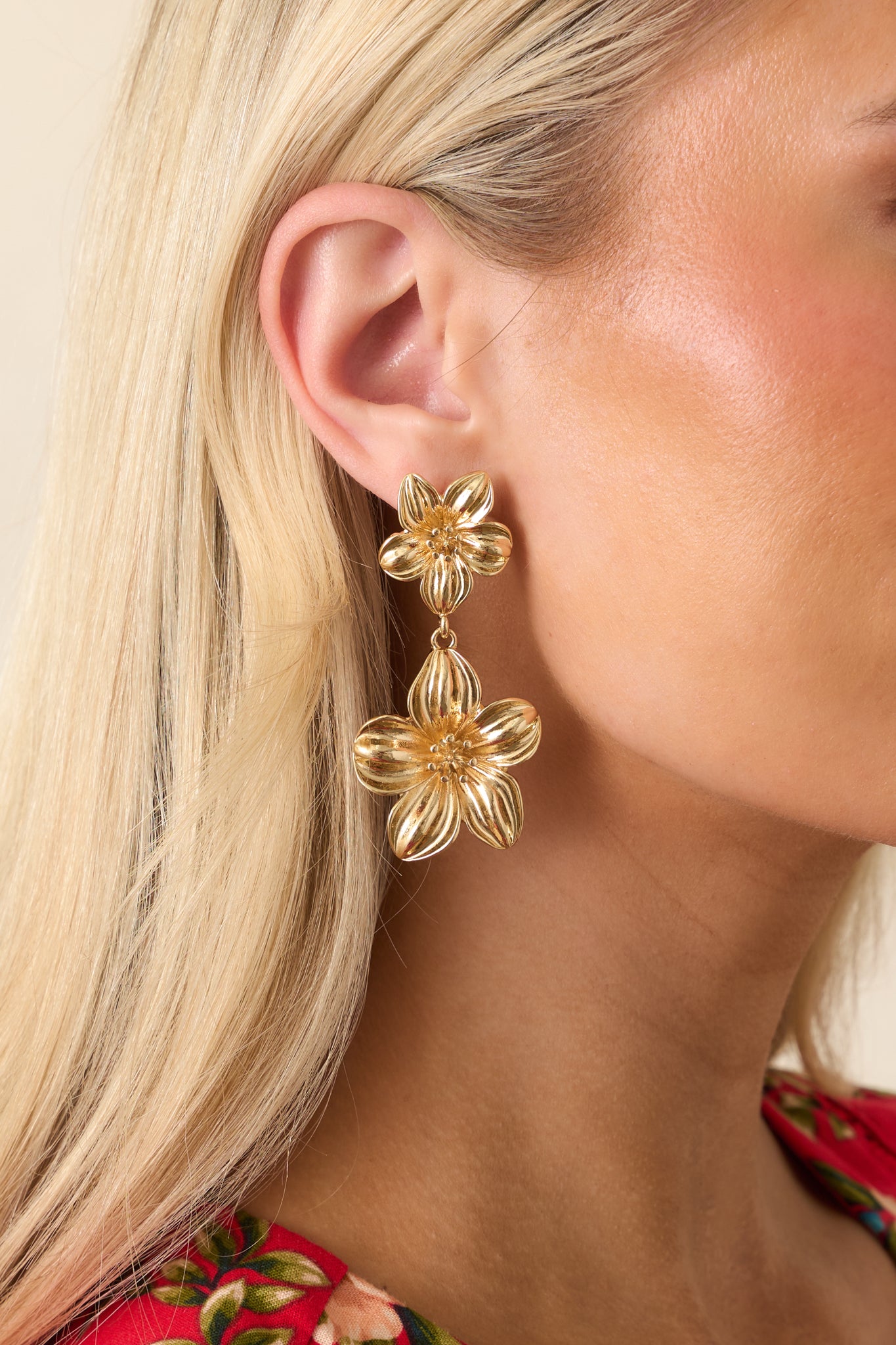 Close-up of the gold flower stud, matching floral drop, and polished earring details.