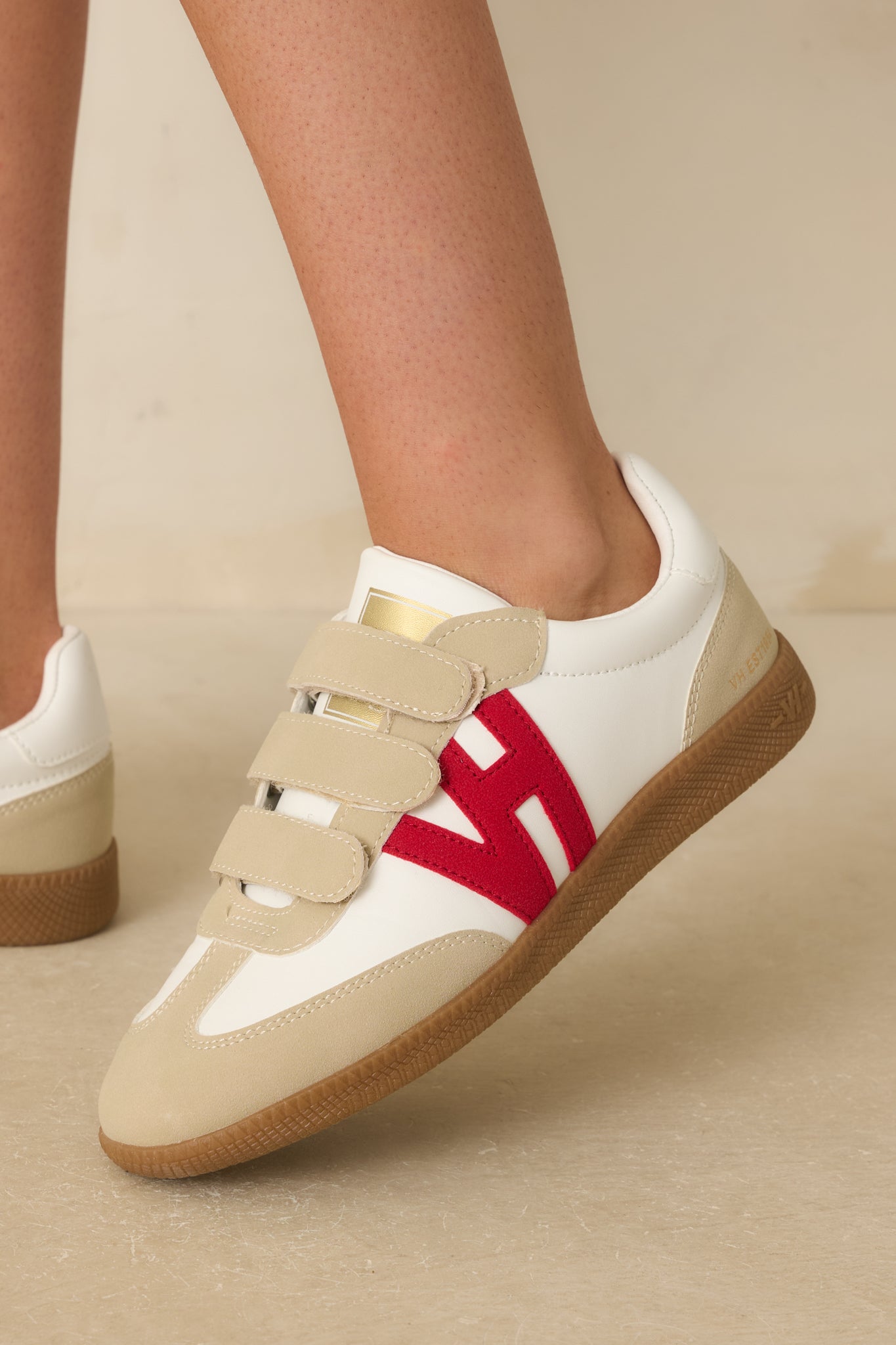 Close-up of the gold logo on the tongue, the red side logo appliqué, and stitching on the ivory upper.