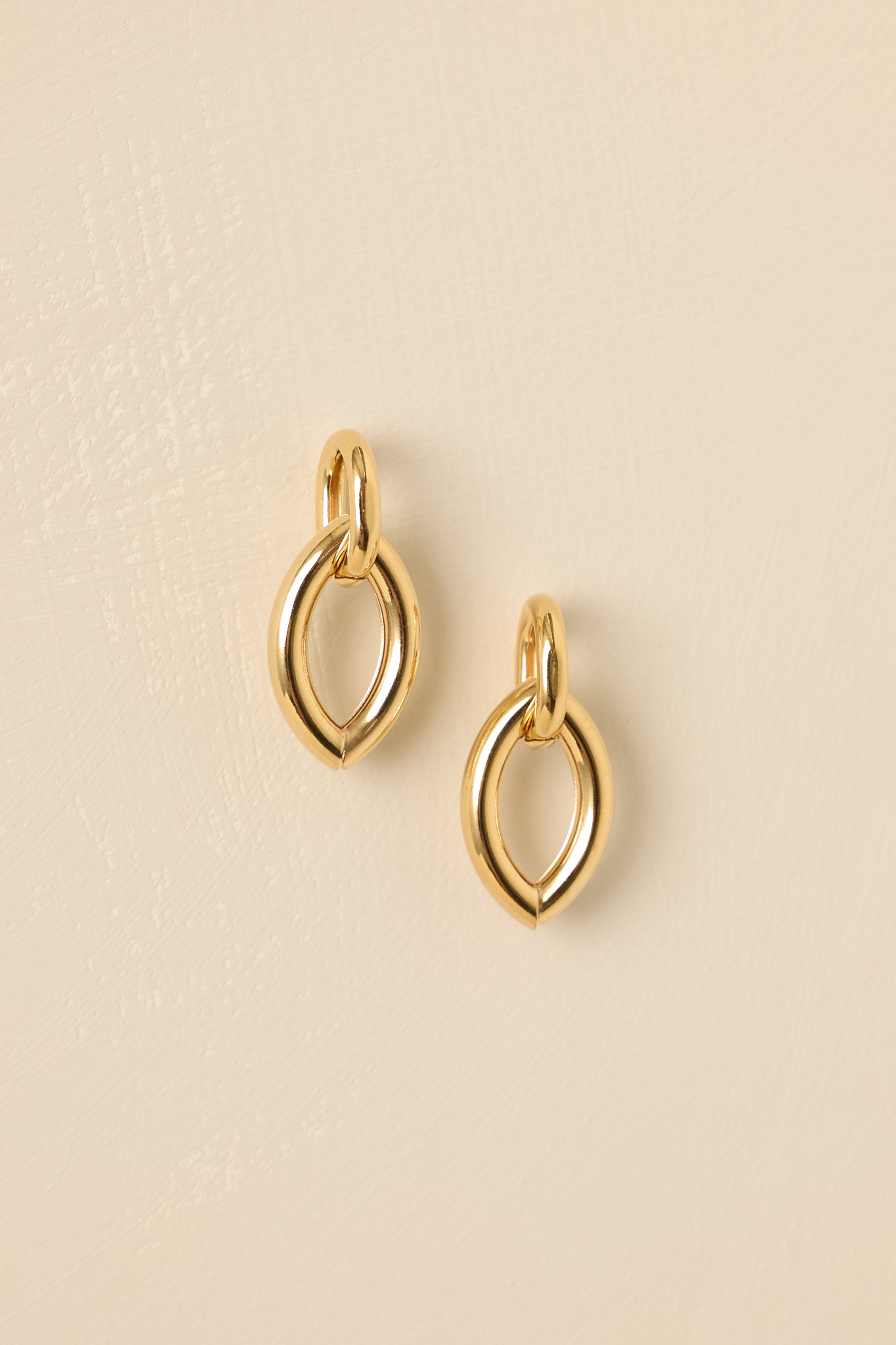 Detailed close-up of the gold marquise earrings focusing on the interlocking pieces, eye-shaped design, and post backings.