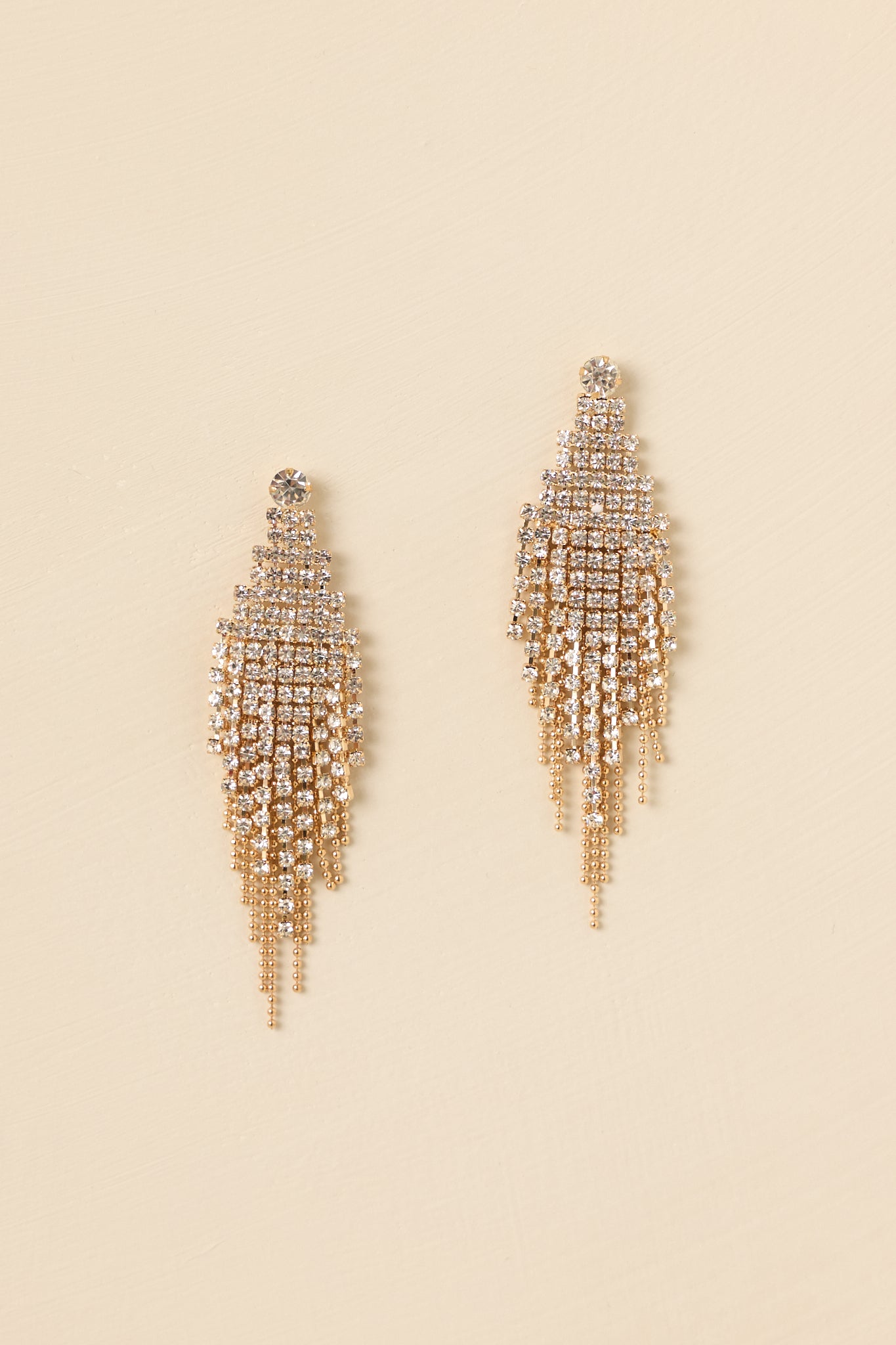 Detailed close-up of the gold and rhinestone earrings focusing on the mesh diamond shape, rhinestone accents, and gold chain fringe.