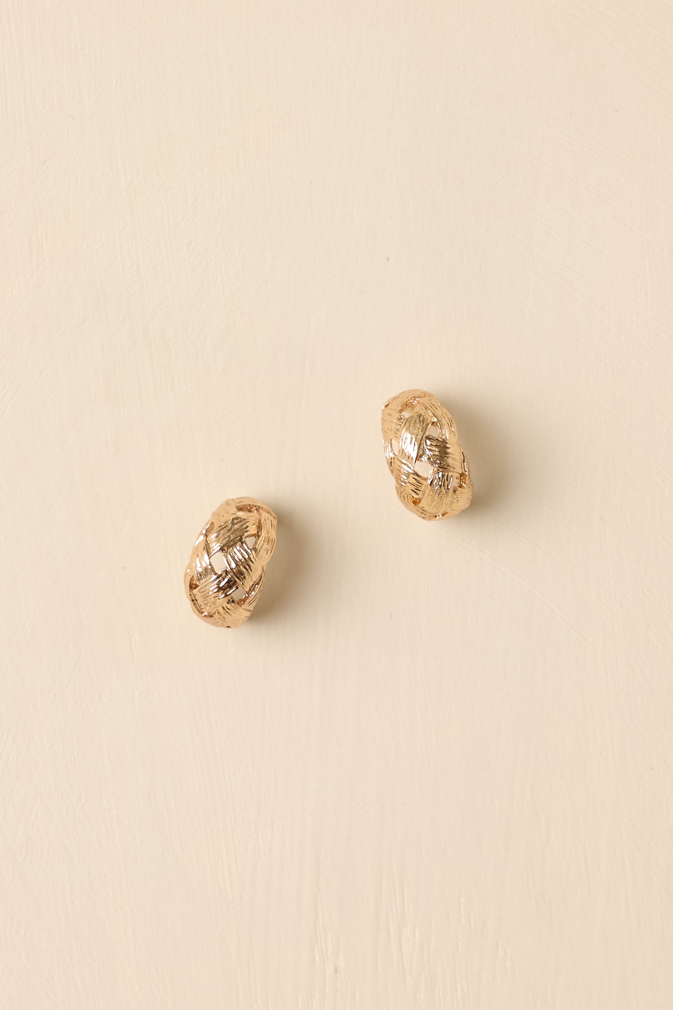 Detailed close-up of the gold-tone hoop earrings focusing on the textured surface and lightweight rounded design.