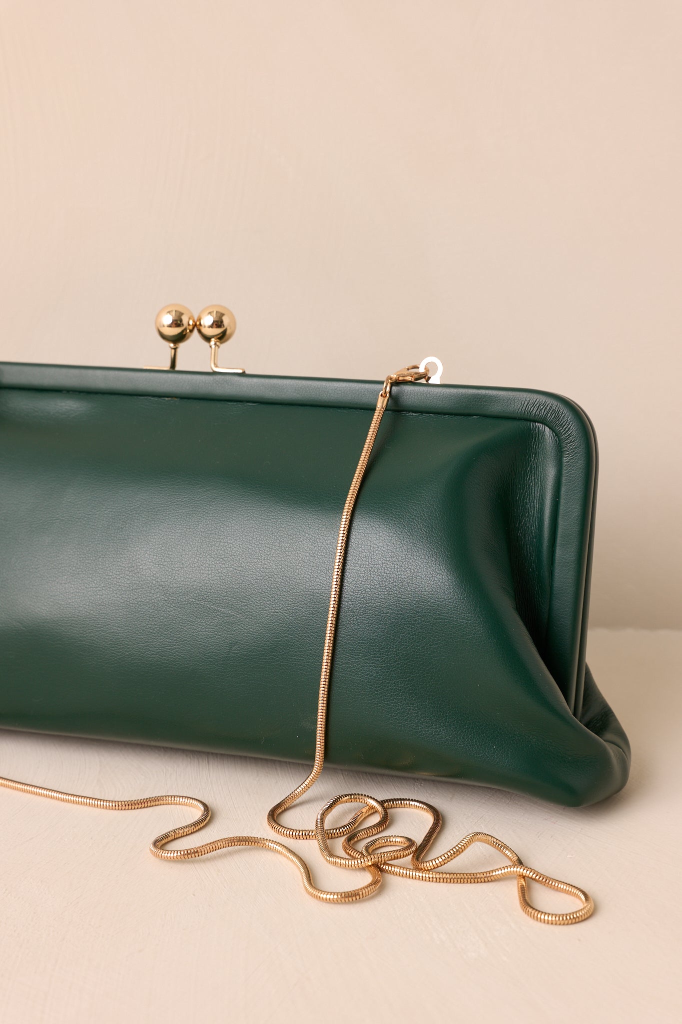 Close-up of the green clutch highlighting the gold kiss-lock closure and featuring soft fabric lining inside.