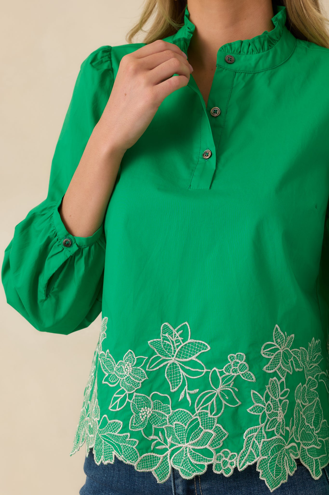 Close-up detail of the green top highlighting floral embroidery along the hem and soft gathered neckline.