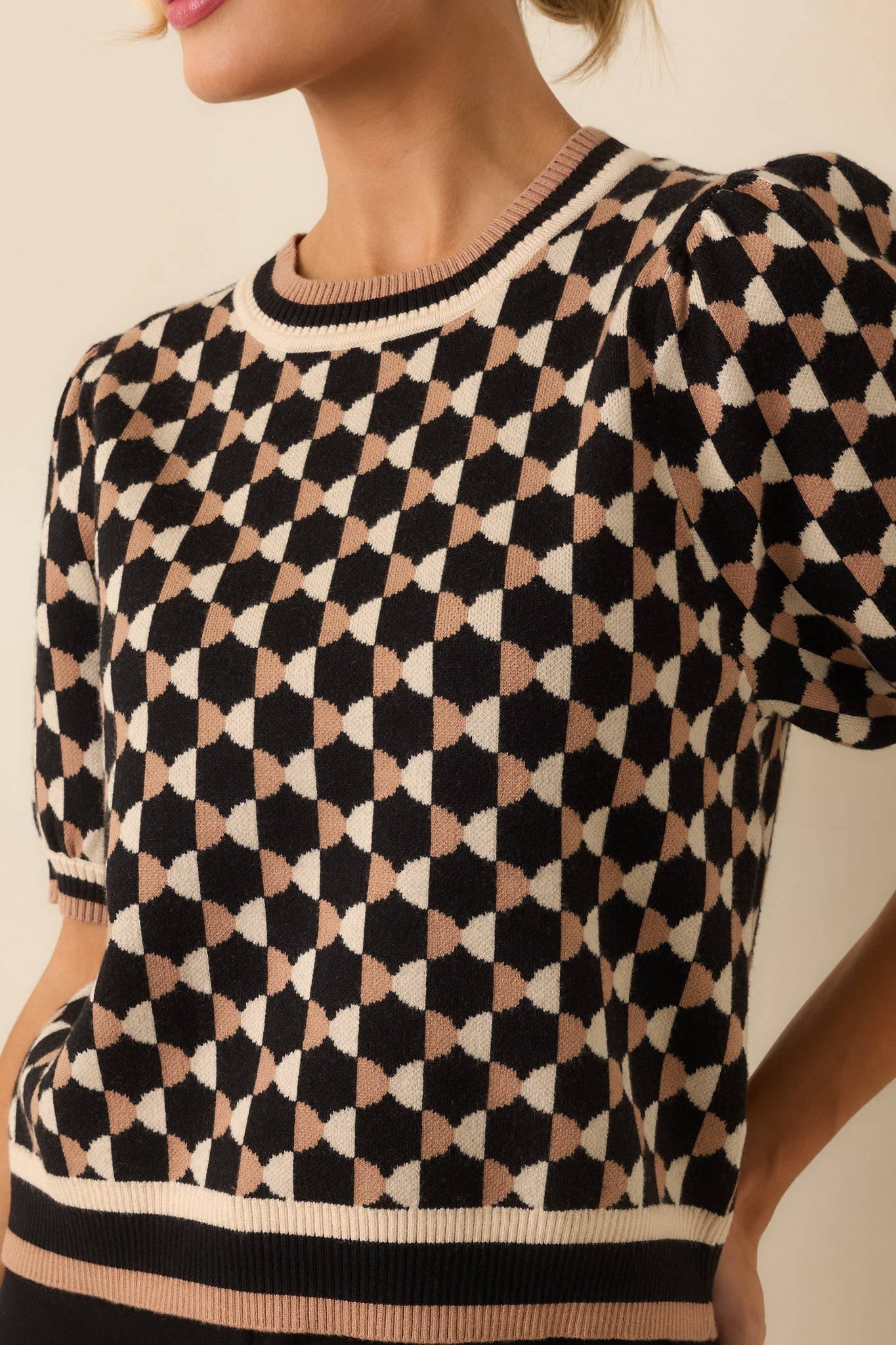 Close-up showing knit fabric texture, black and beige geometric print, ribbed hems, and puff sleeve detailing.