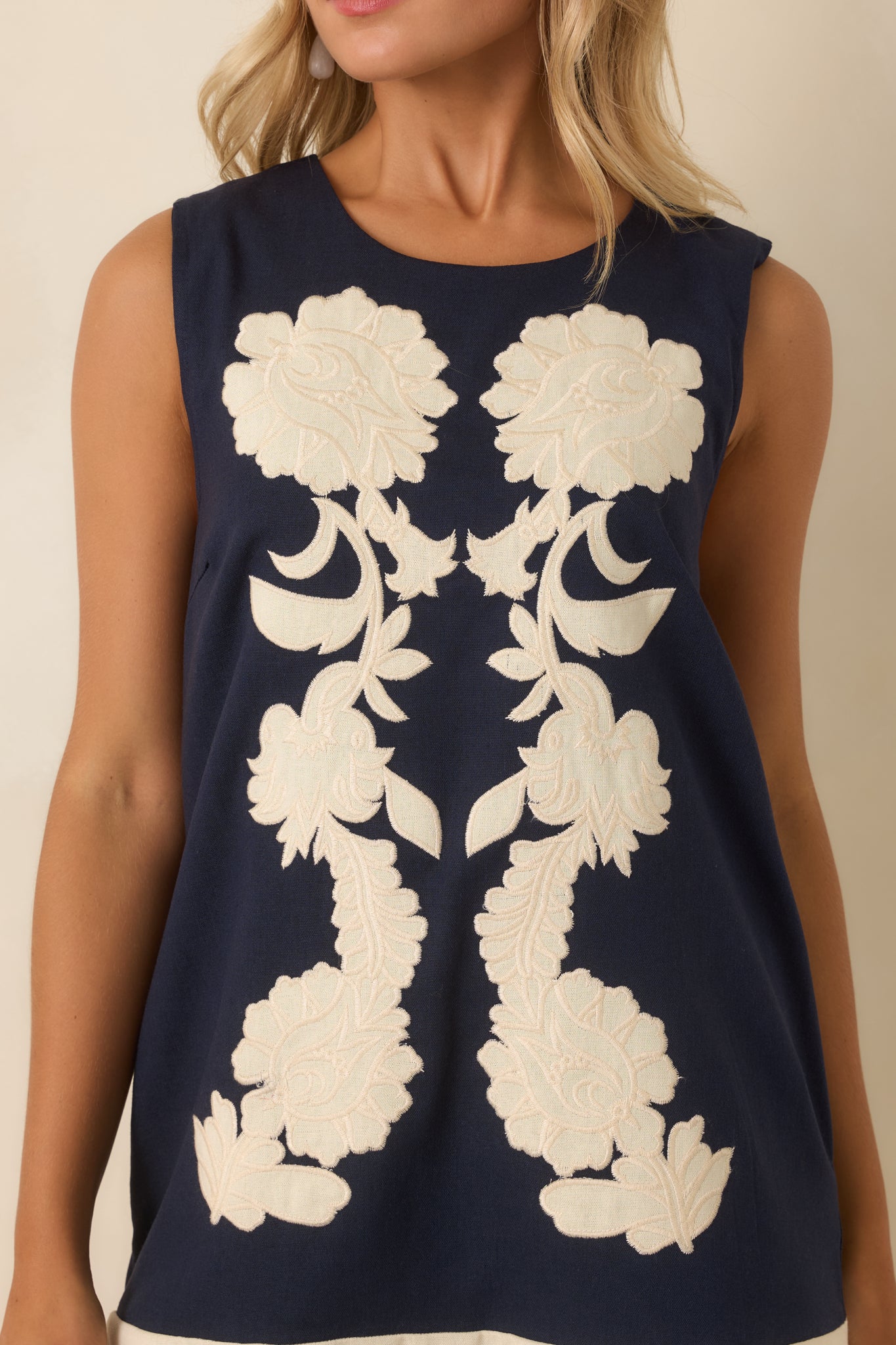Close-up of the navy floral dress highlighting oversized ivory appliqué flowers, embroidered texture, round neckline, and detailed stitching.