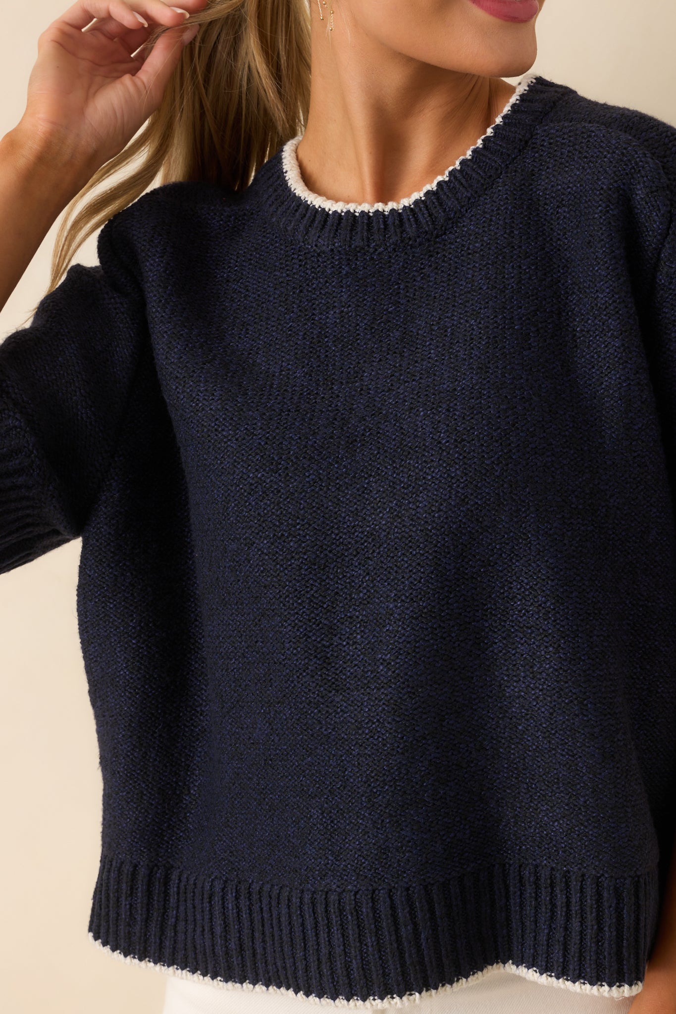 Close-up of navy knit fabric showing ivory contrast trim and ribbed texture.