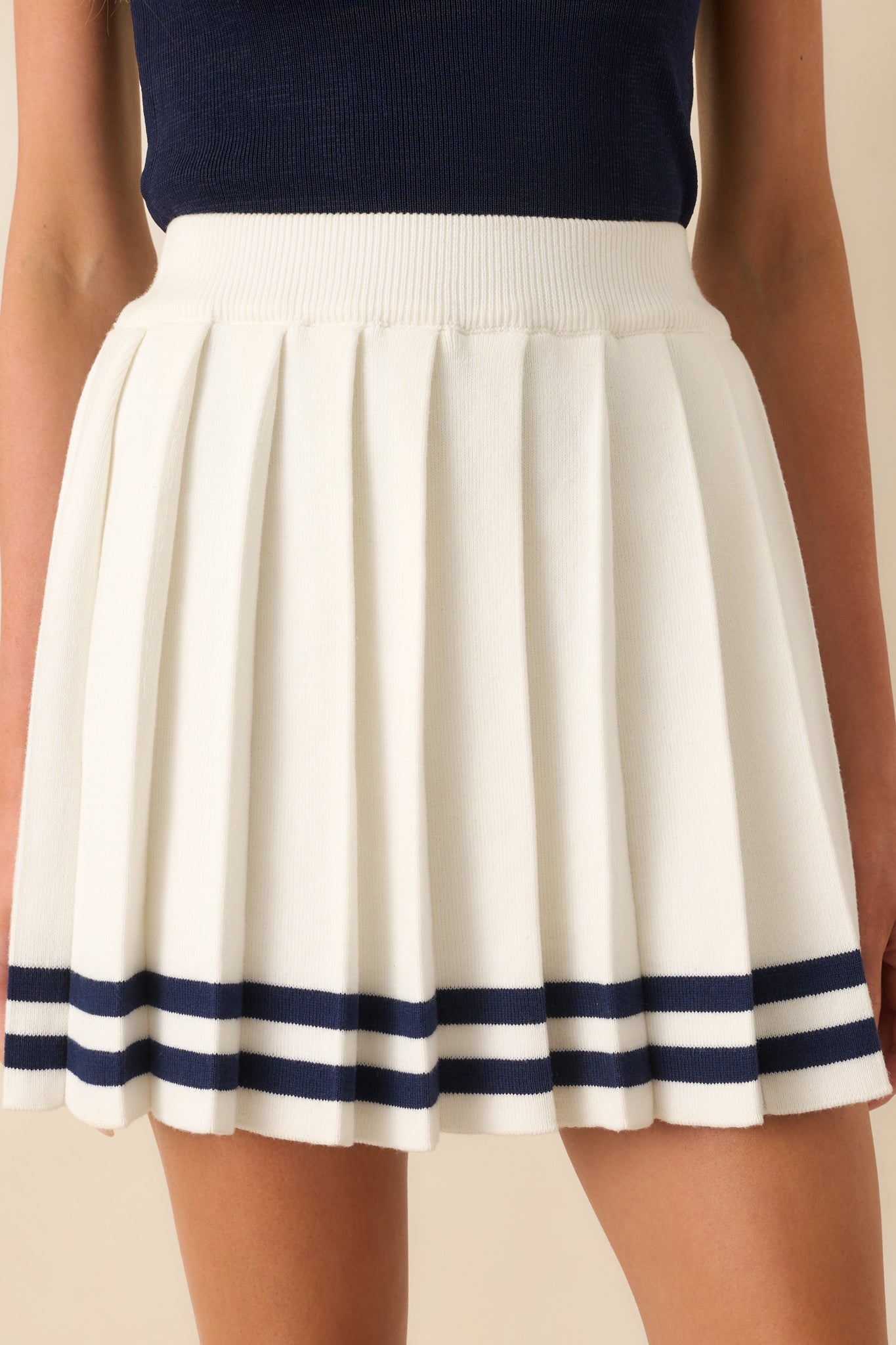 Close-up of the navy stripes along the bottom hem and fine pleating in the knit fabric.