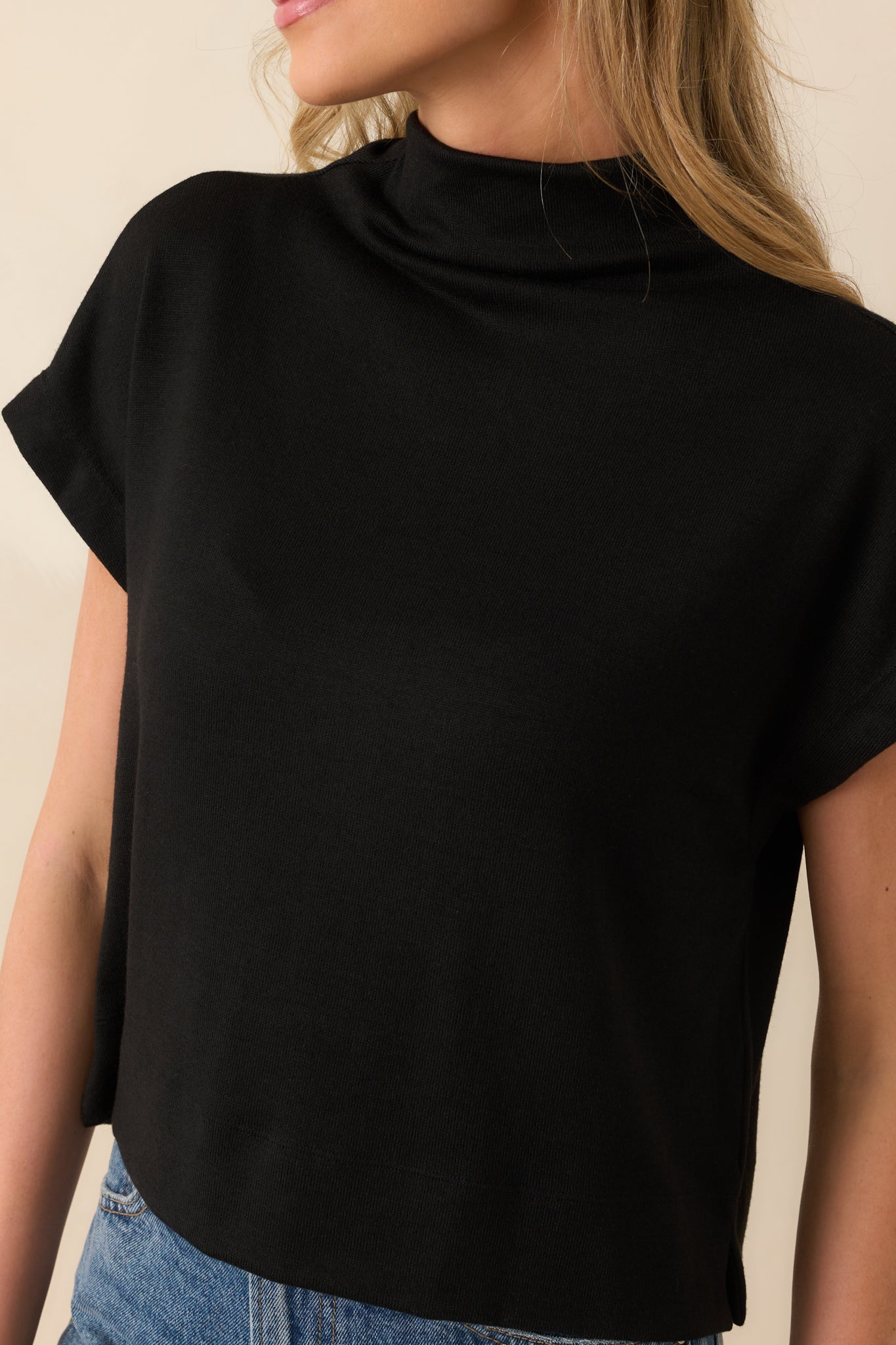 Close-up of the neckline and upper chest area showing the soft roll of the mock neck and fabric texture.
