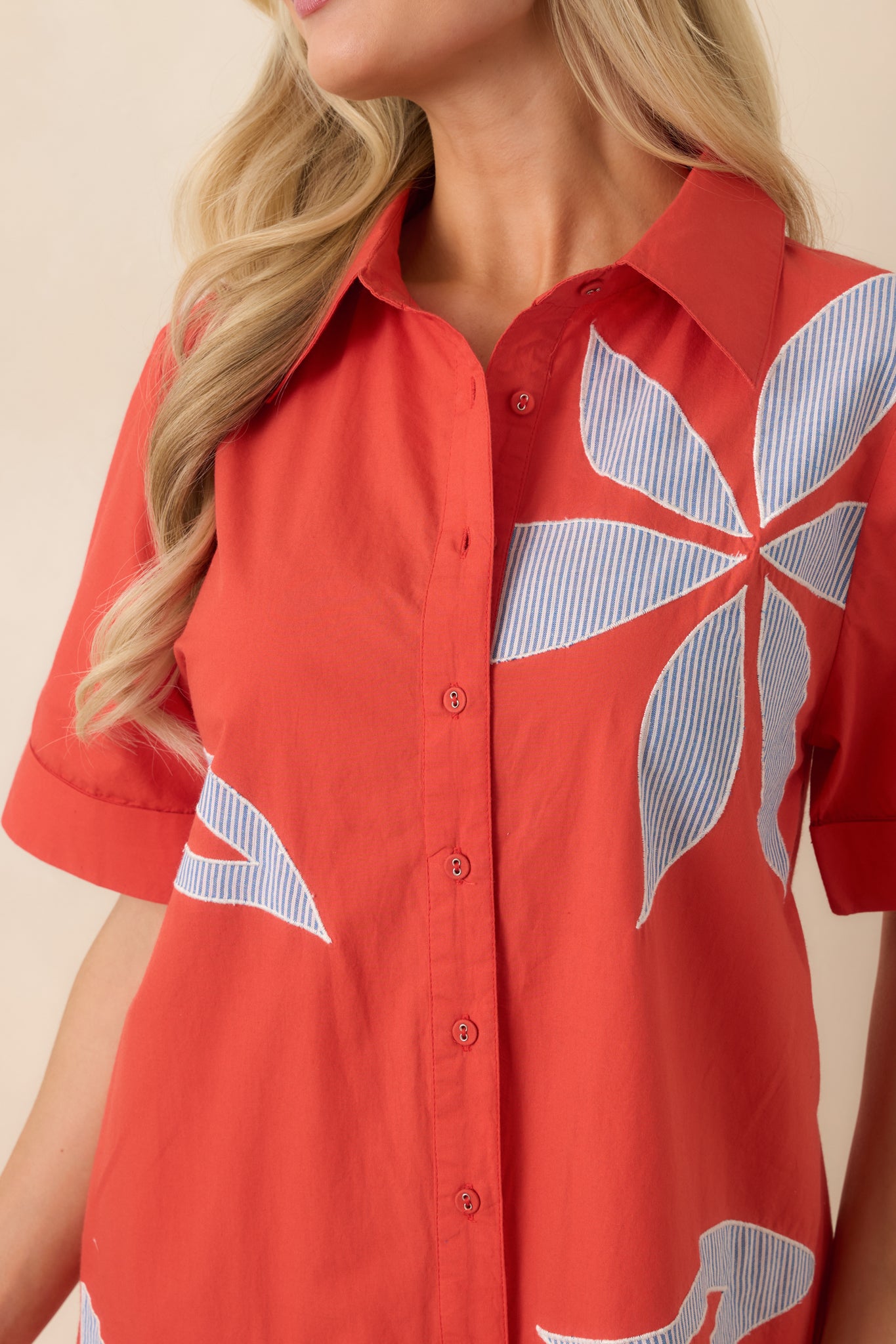 Close-up of bold floral appliqué on light blue and white striped fabric with textured dimension.