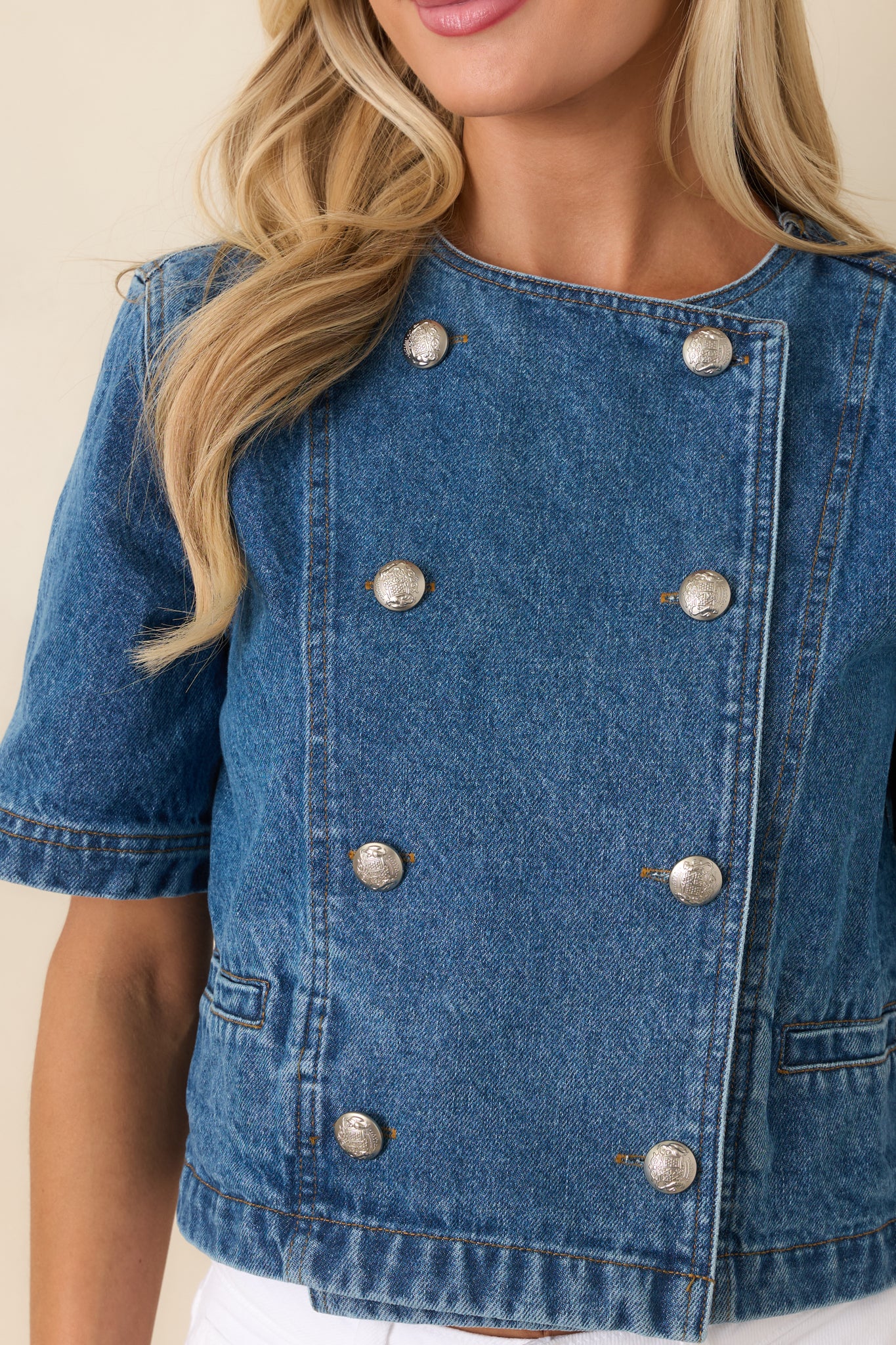 Close-up of medium wash denim top showcasing the gold-tone buttons, stitching, and structured fabric texture