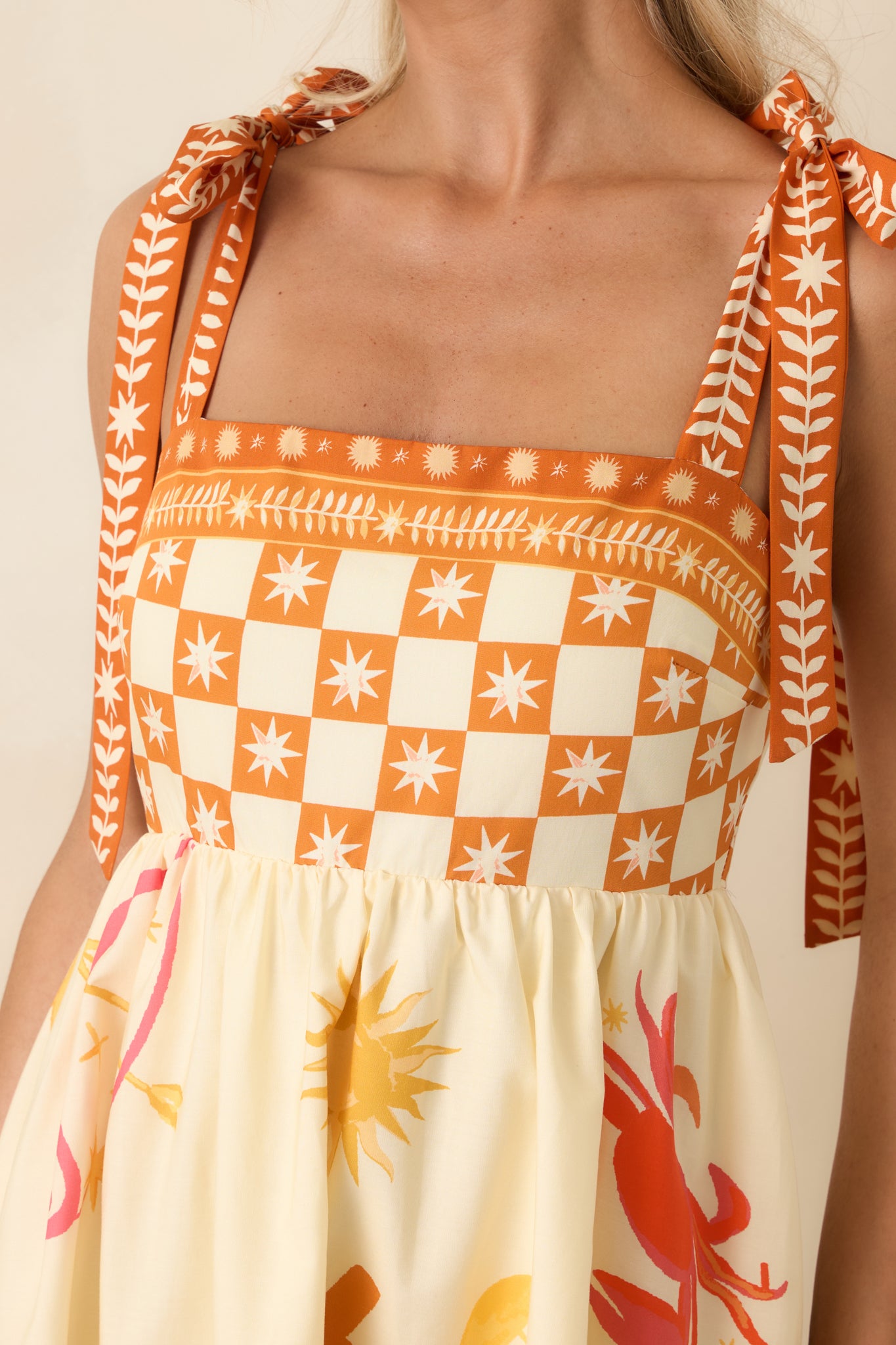 Close-up of fitted bodice with adjustable tie straps and structured neckline on ivory maxi dress.