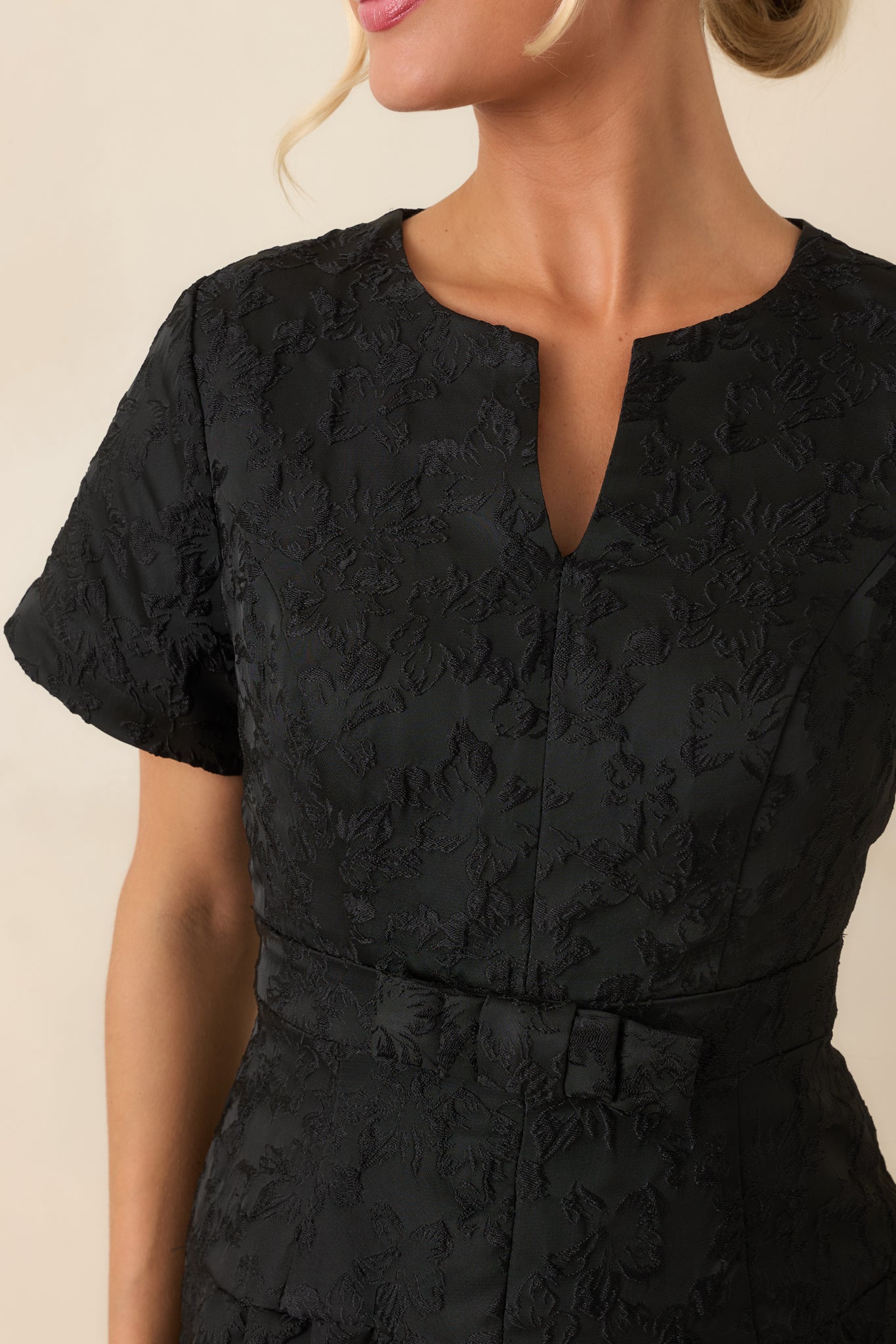 Close-up view of the tonal floral jacquard, split neckline, and petite bow waistband detail.