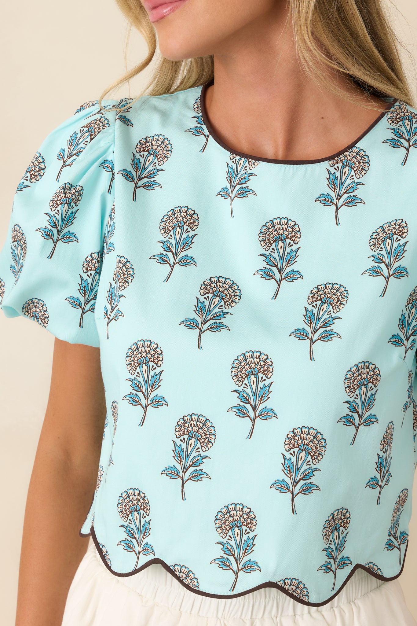 Close-up view of the floral pattern, scalloped hem, and chocolate brown piping details.