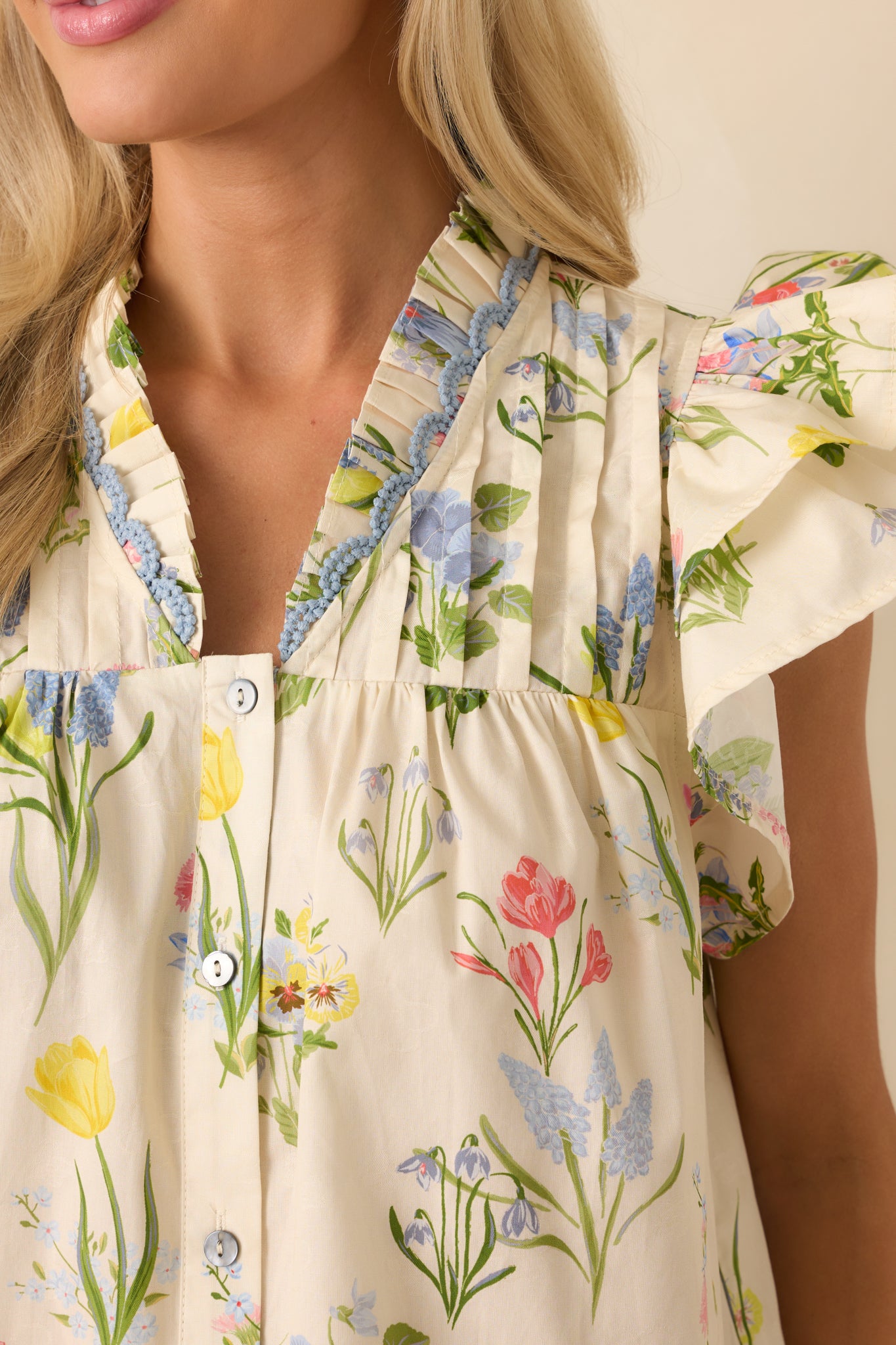 Close-up of the ivory top’s floral print and pintuck stitching, showing fabric texture and color variation in detail.