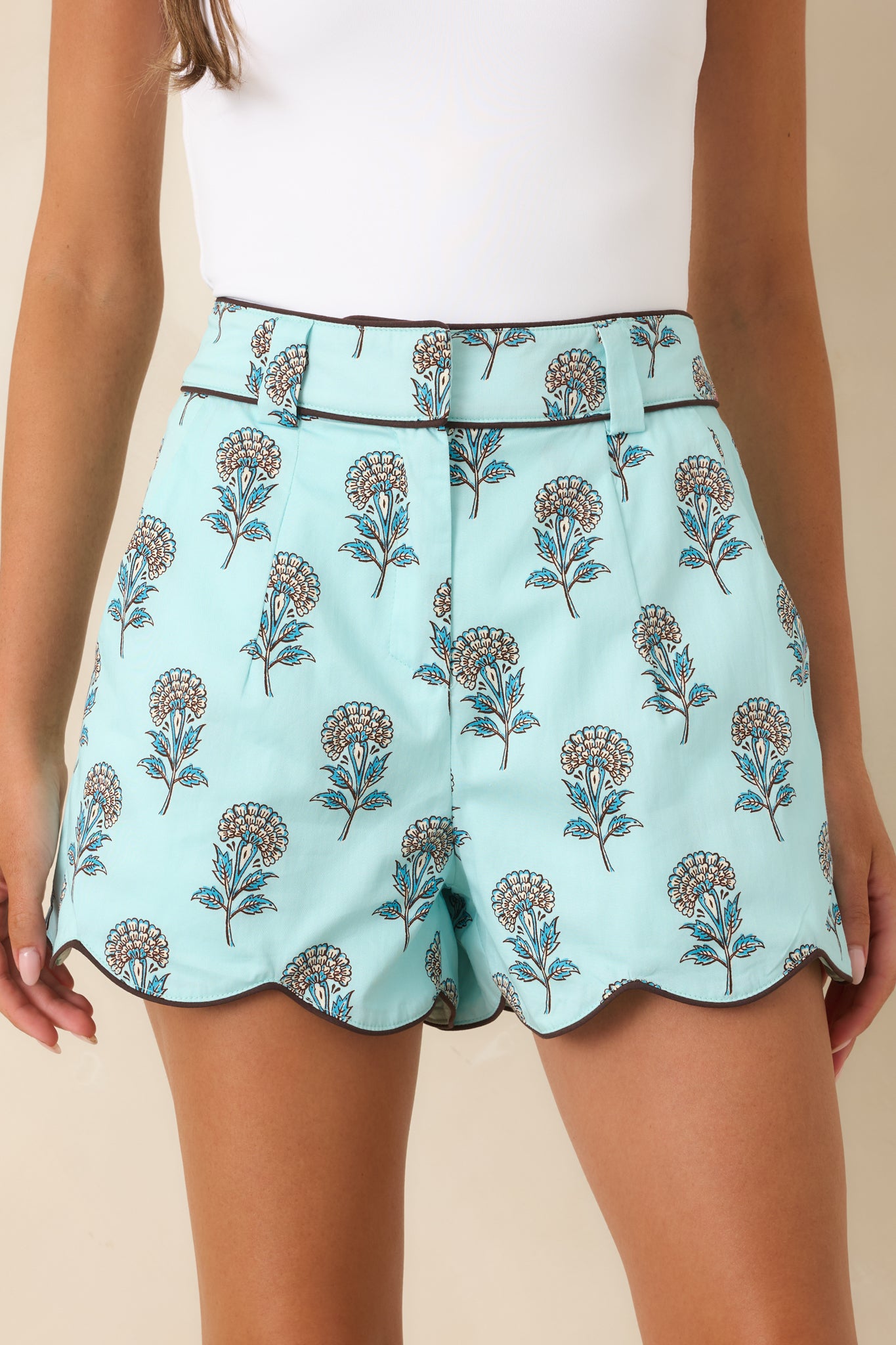 Close-up view of the floral print, coordinating belt, brown piping, and scalloped hem detail.