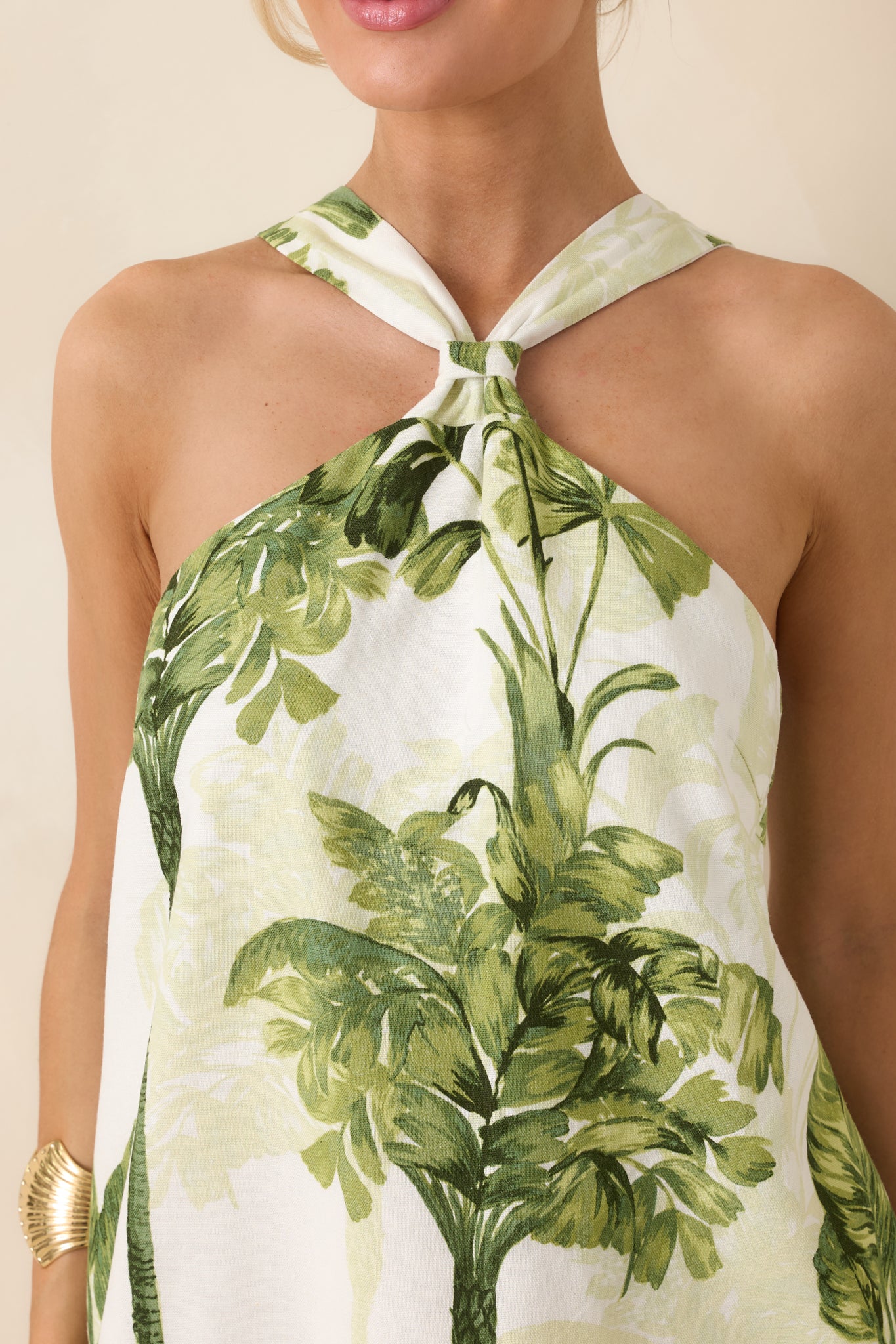 Close-up of green tropical palm print on ivory woven fabric with visible grommet accents and self-tie bow detail.