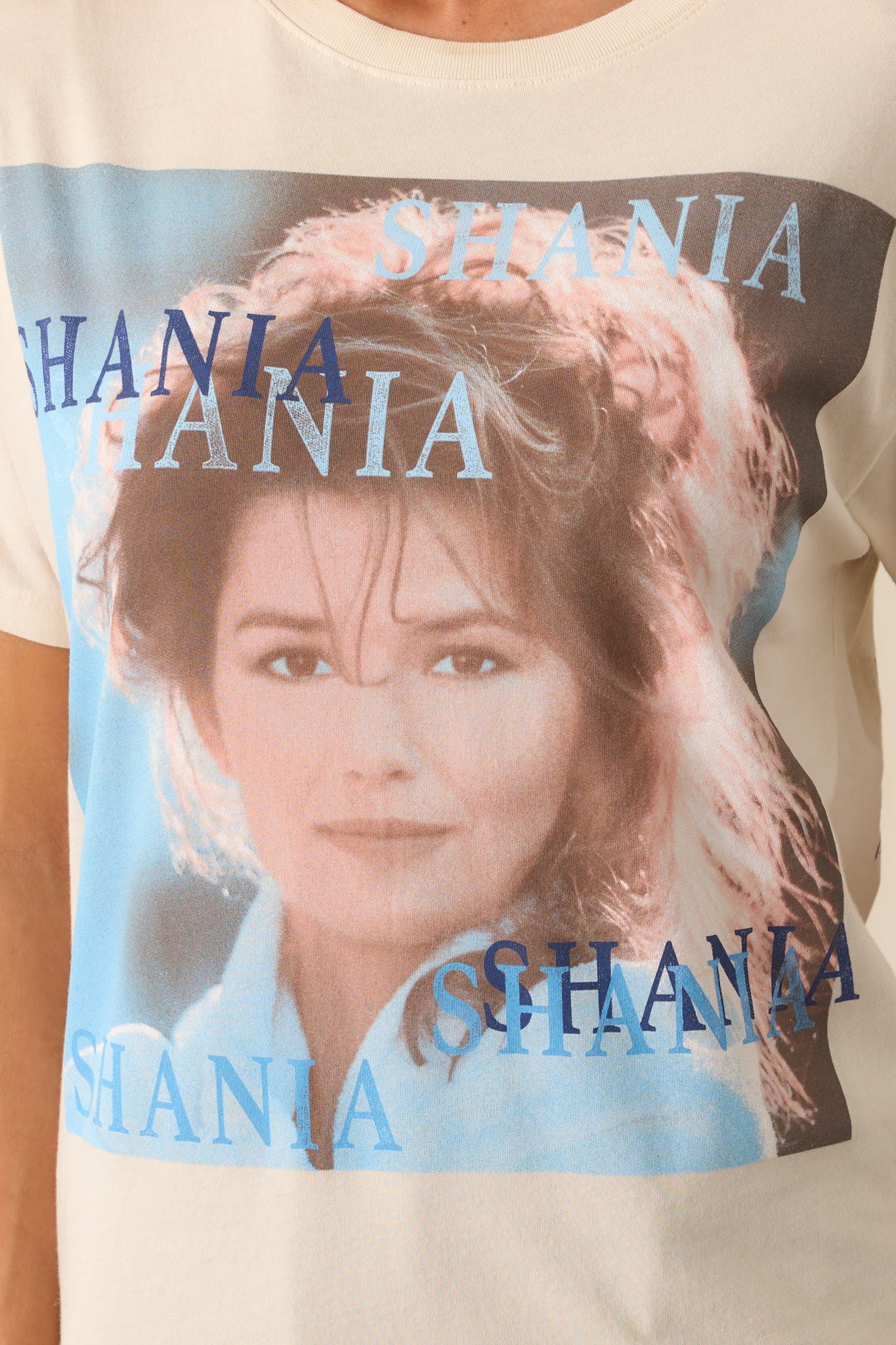 Close-up of the ivory tee's front album cover graphic, showing intricate details of the artwork printed on the fabric