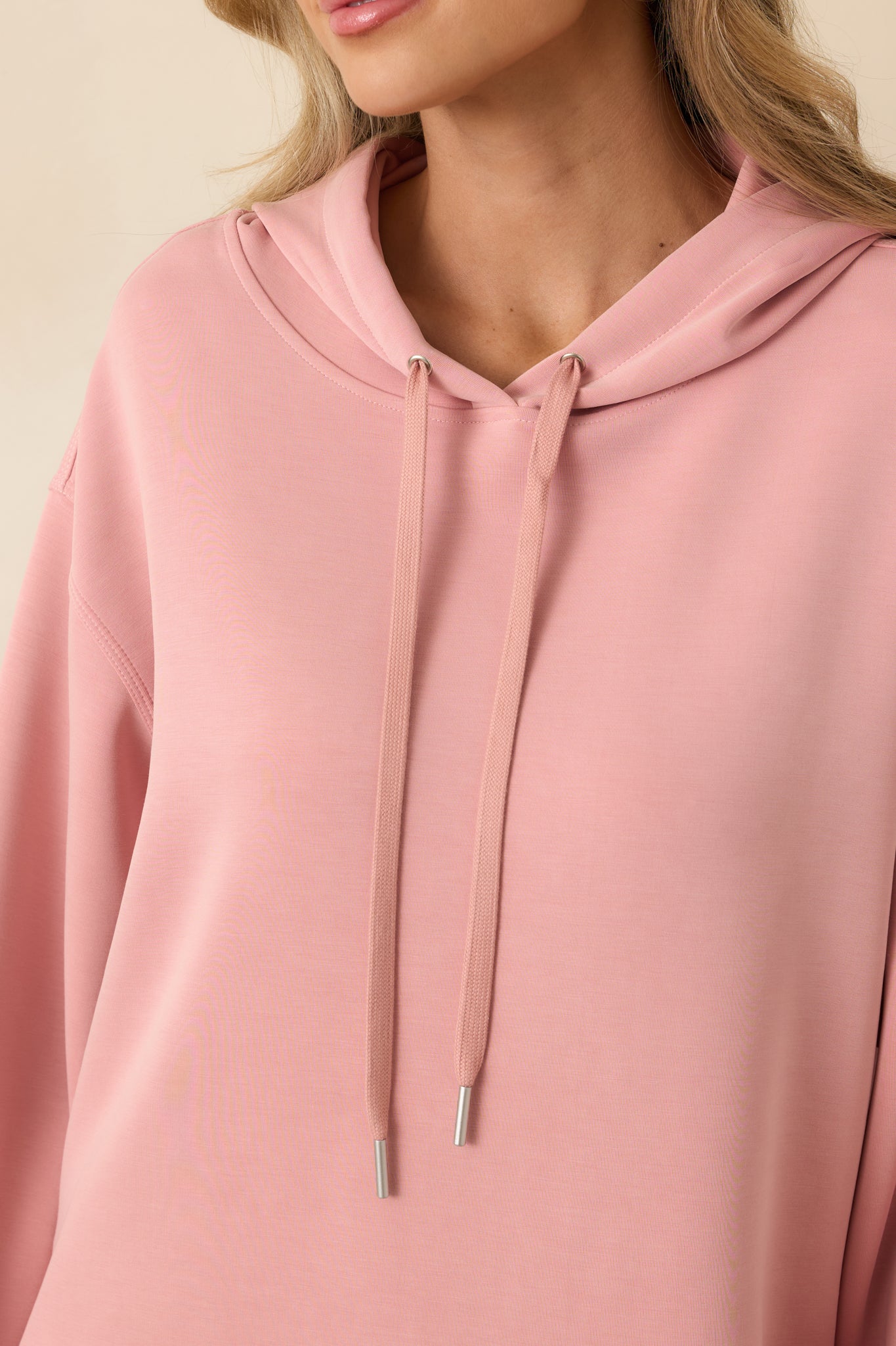 Close-up of ribbed hem and knit texture on powder pink hoodie.
