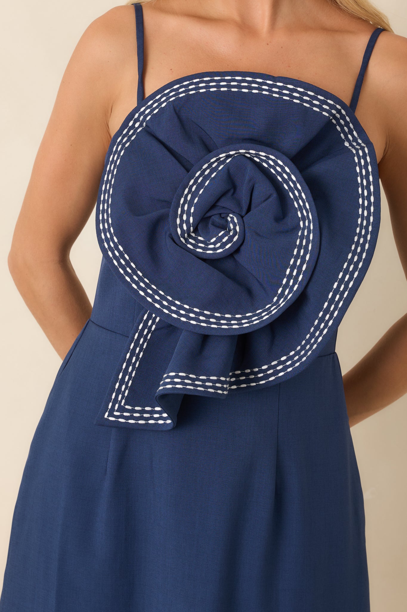 Close-up view of the oversized rosette, contrast white stitching, and textured fabric details on the dress.