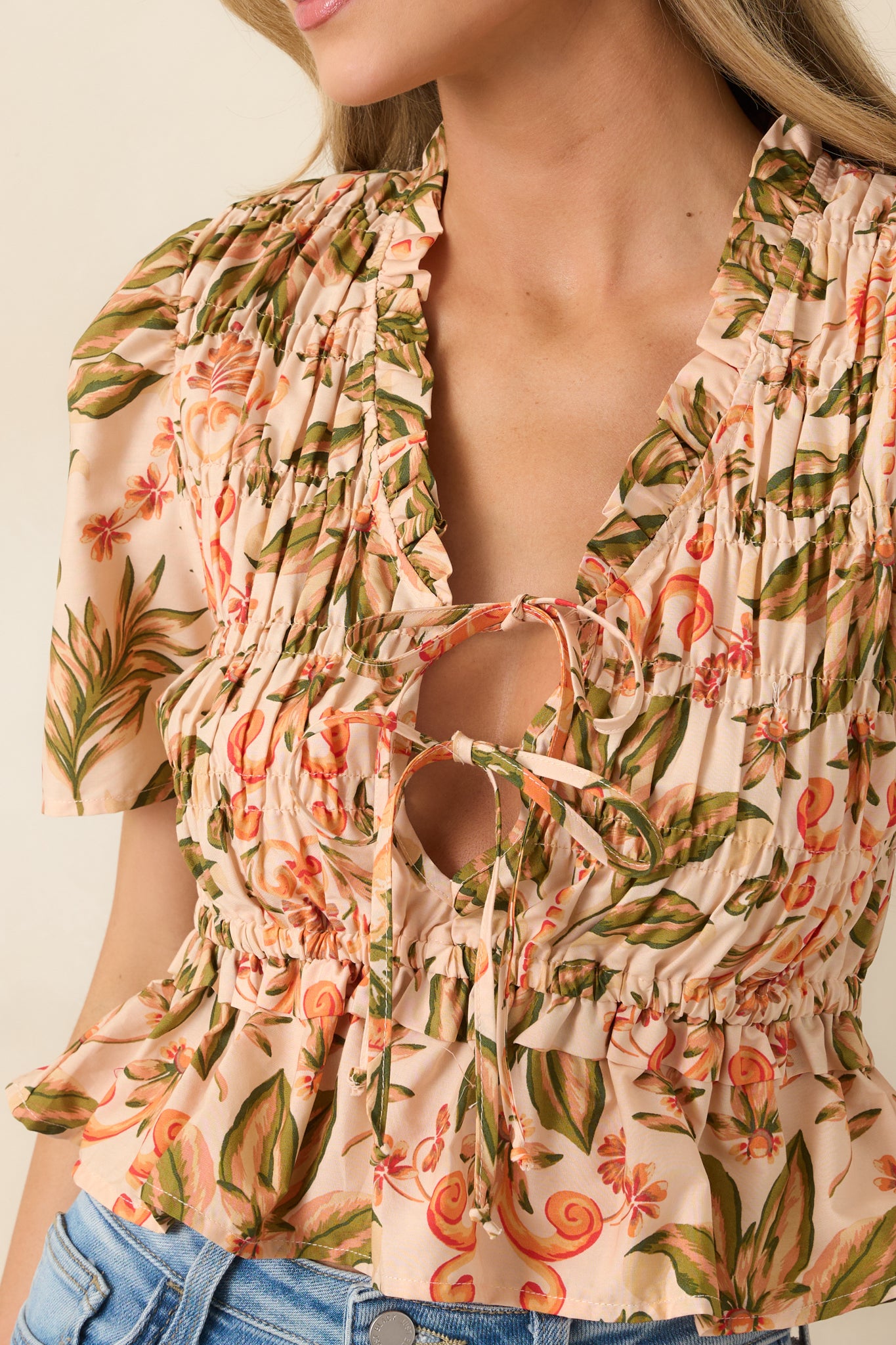 Close-up of ruffled V-neckline with adjustable ties and smocked texture.