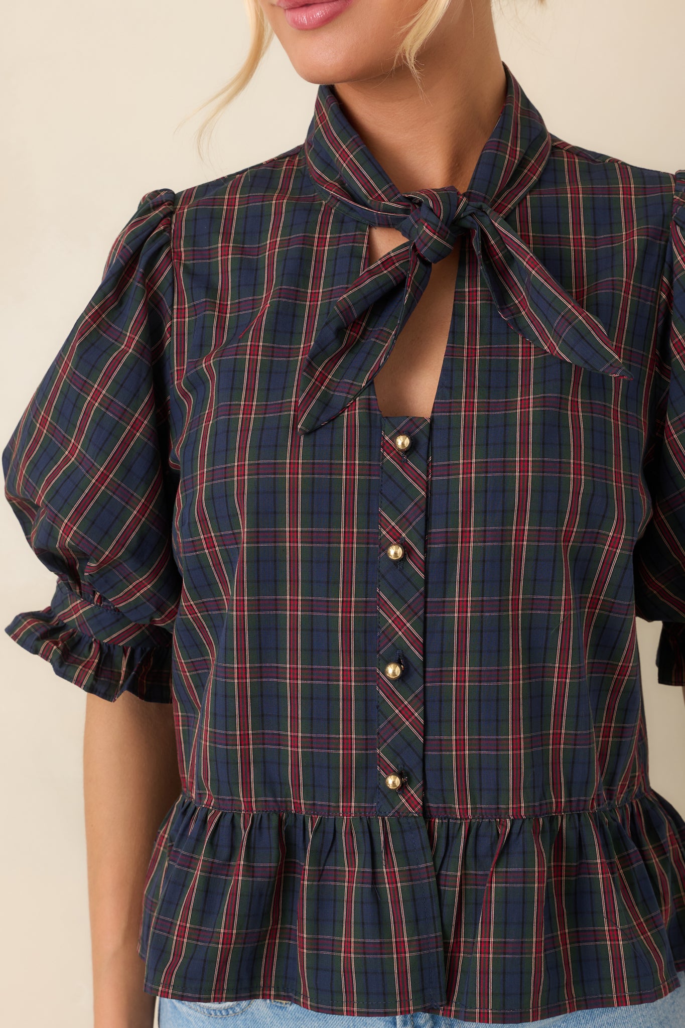 Close-up view of the self-tie neckline, gold-tone buttons, and ruffled cuff detailing.