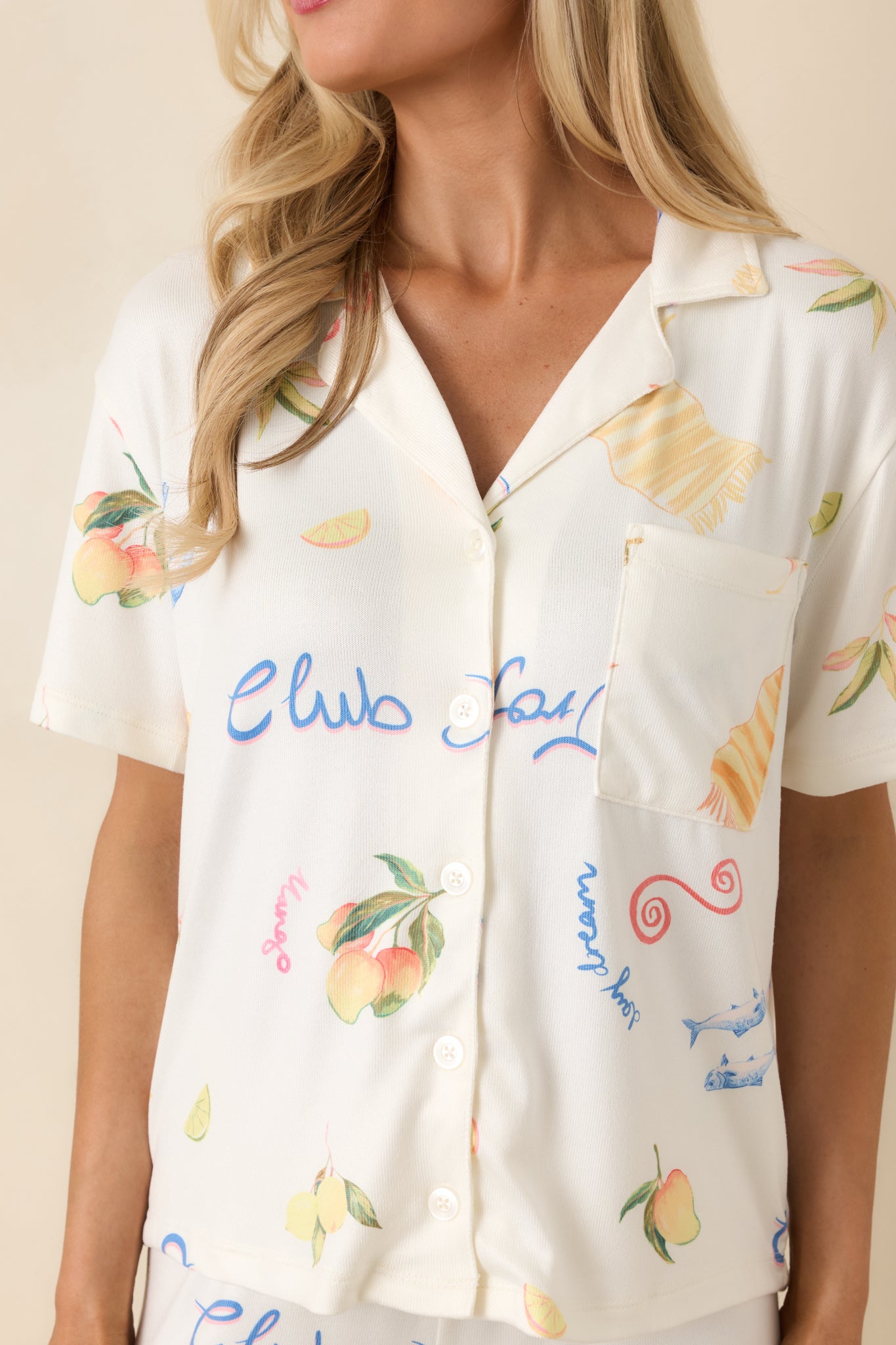 Close-up of silky fabric pajama top showcasing tropical print with citrus, beach icons, and button details