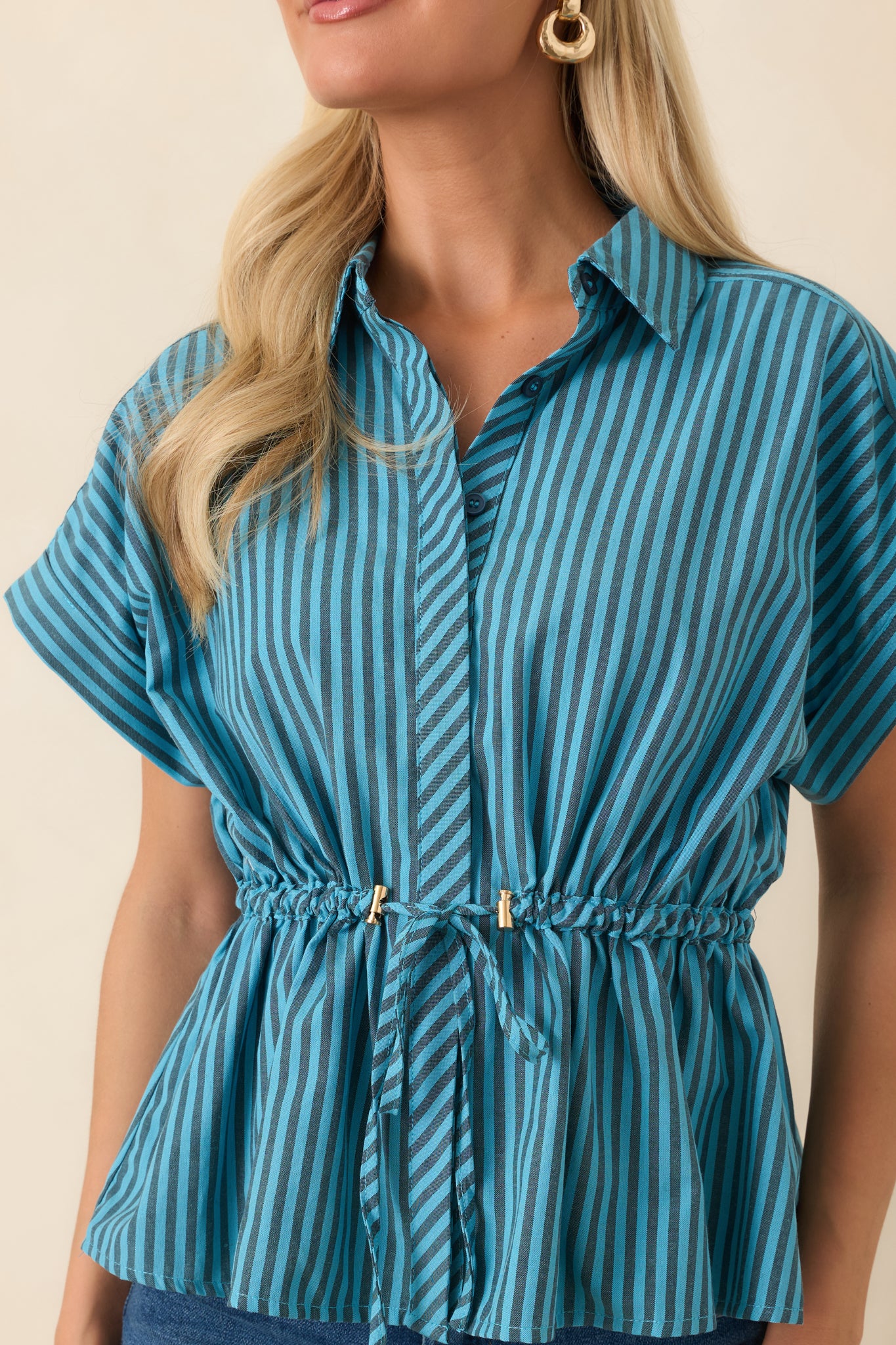 Close-up view of the striped fabric, collar detail, and gold-tone drawstring toggles.
