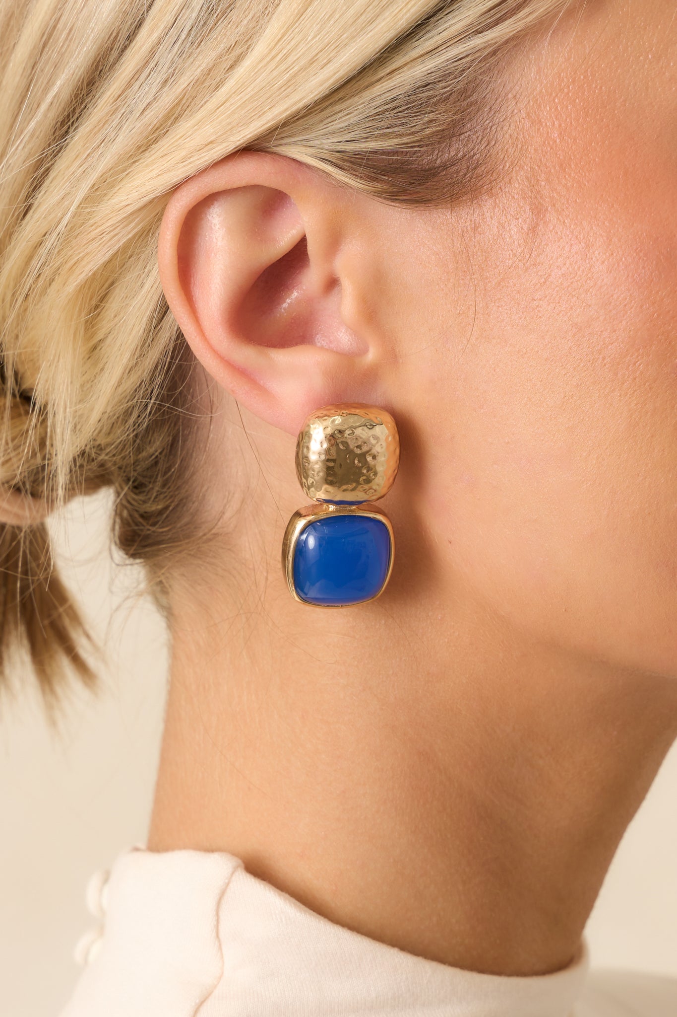Close-up of the blue earrings highlighting the gold textured square stud, blue stone square drop, and secure post backing.