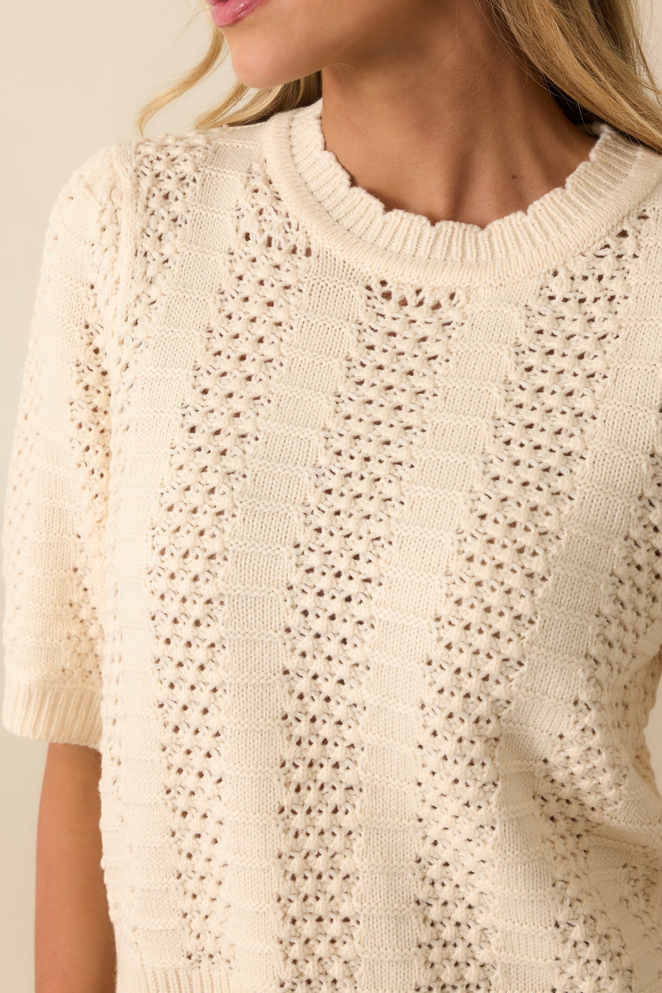 Close-up of the crochet-knit panels, ribbed sections, and fabric texture on the ivory sweater.