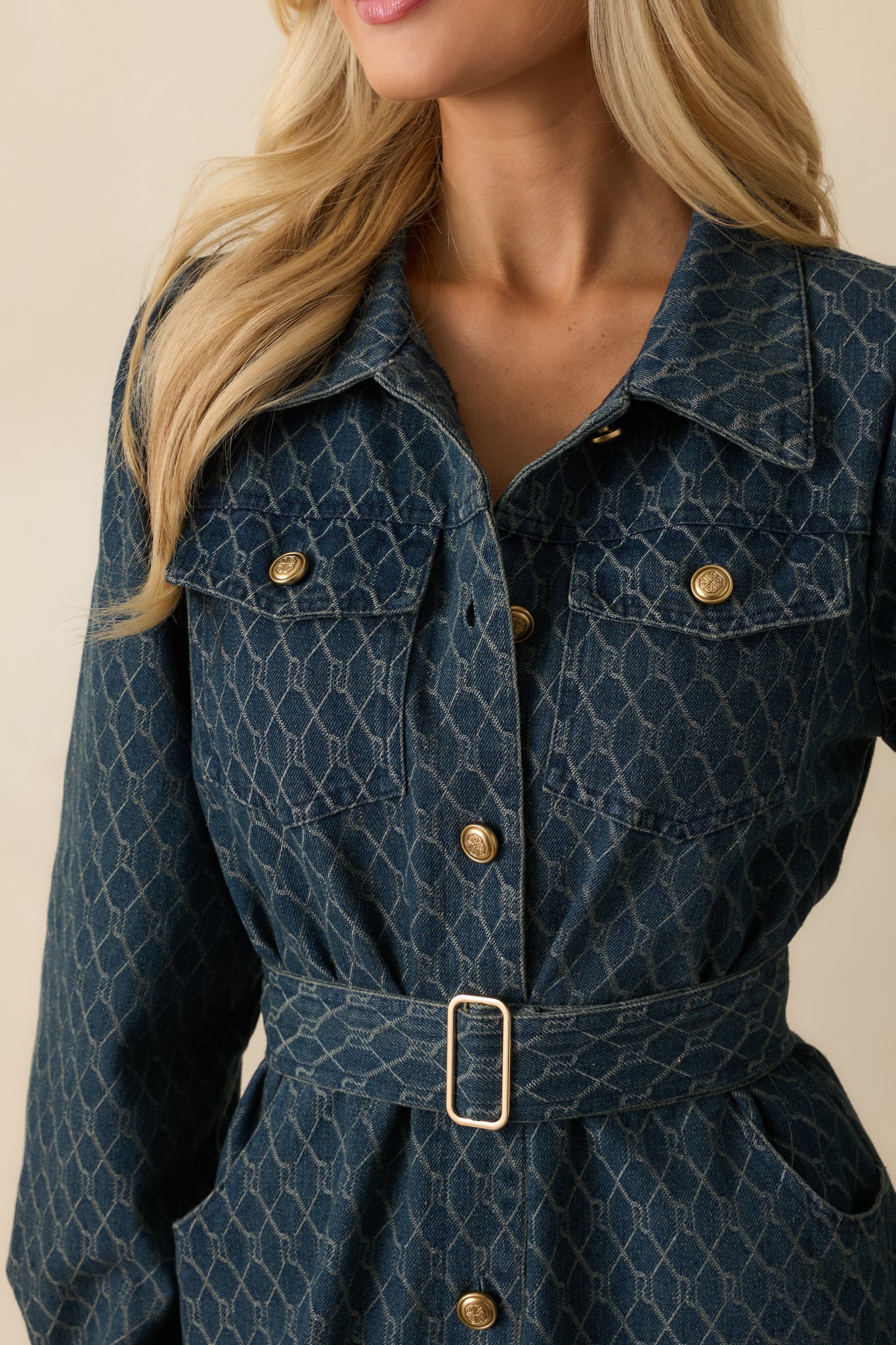 Close-up of the denim fabric showing embossed buttons, chest pocket detailing, and textured weave.