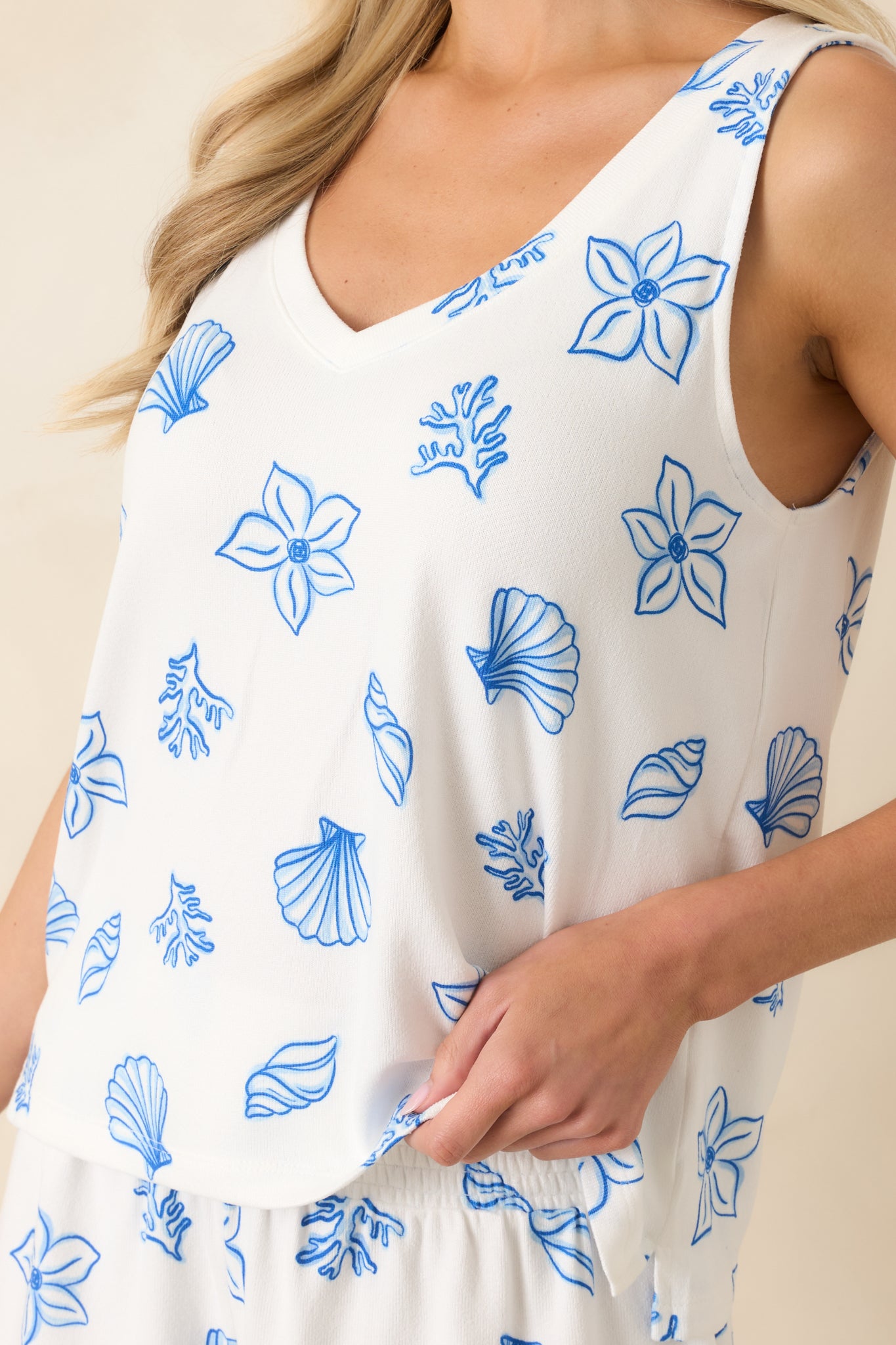 Close-up of the fabric showing the intricate blue seaside print with seashell, coral, and floral designs on a white base.