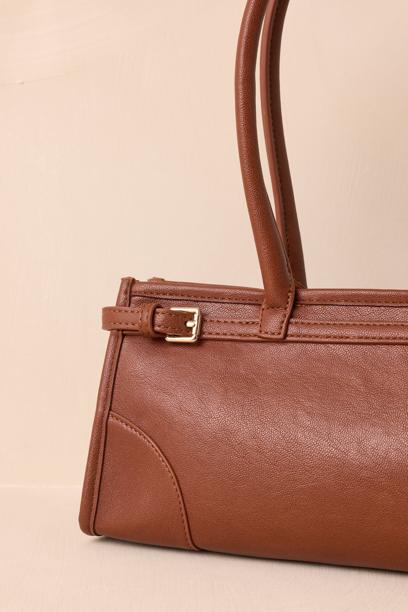 Detailed close-up of the gold hardware, belted side accents, and textured faux leather exterior.