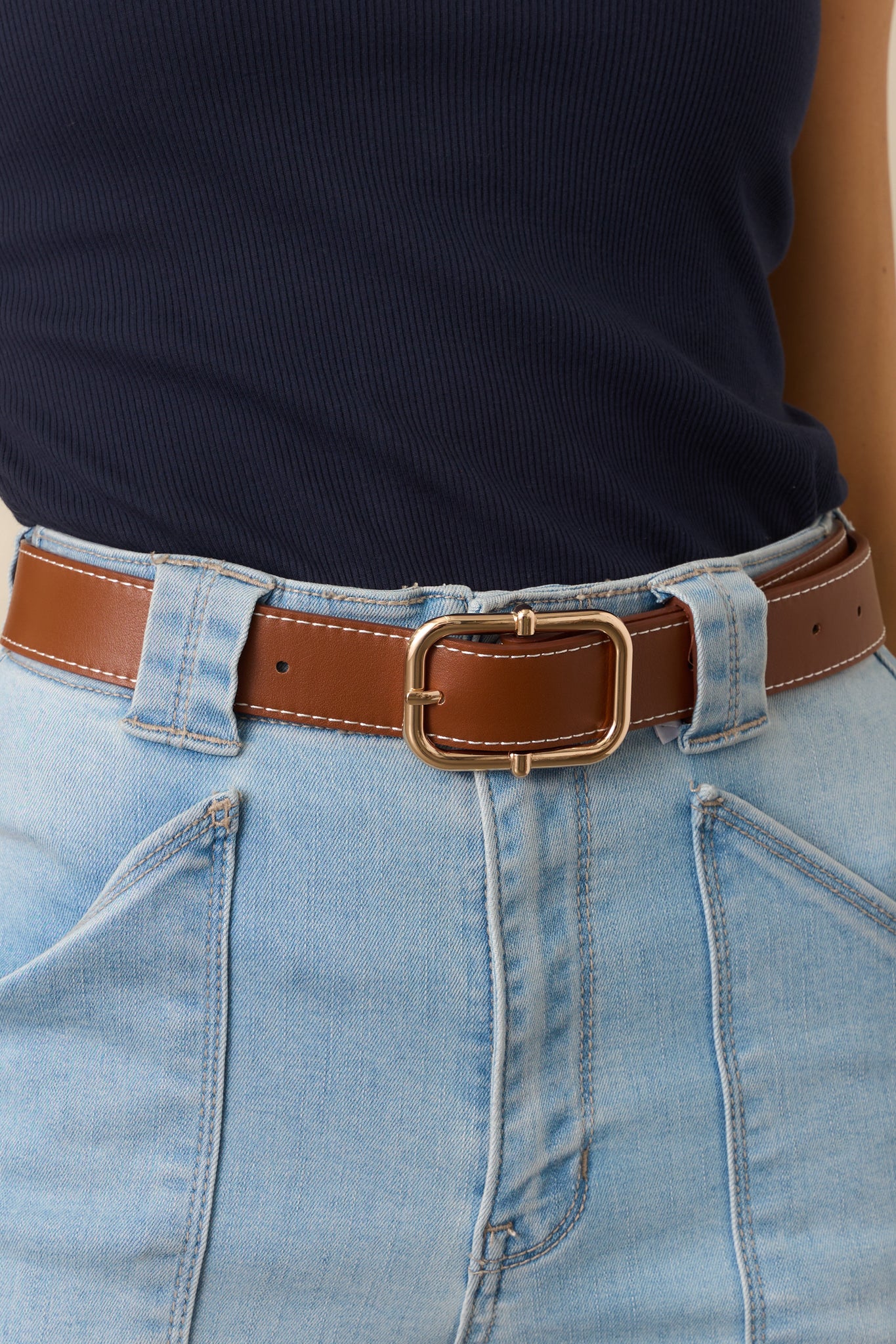 A close-up of the gold square pin buckle on the brown faux leather belt, showcasing its polished finish and sturdy design.