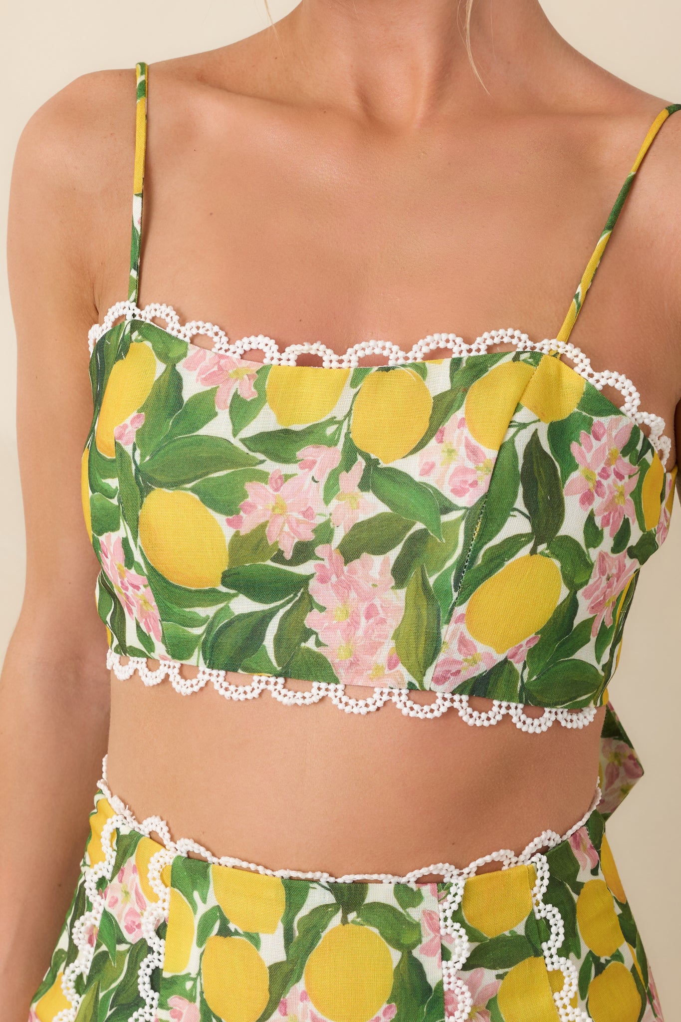 Close-up of the yellow woven fabric, scalloped lace trim, lace inset panels, and precise stitching along the fitted bodice.