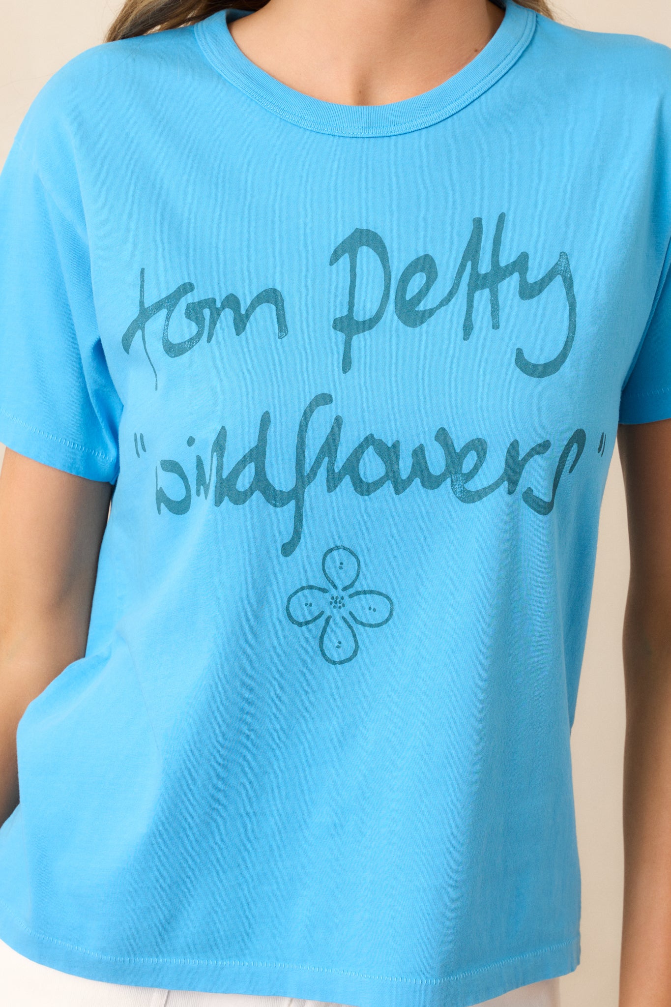 A close-up of the reimagined "Wildflowers" record graphic on this blue tee, showcasing the bold design and the softness of the fabric.