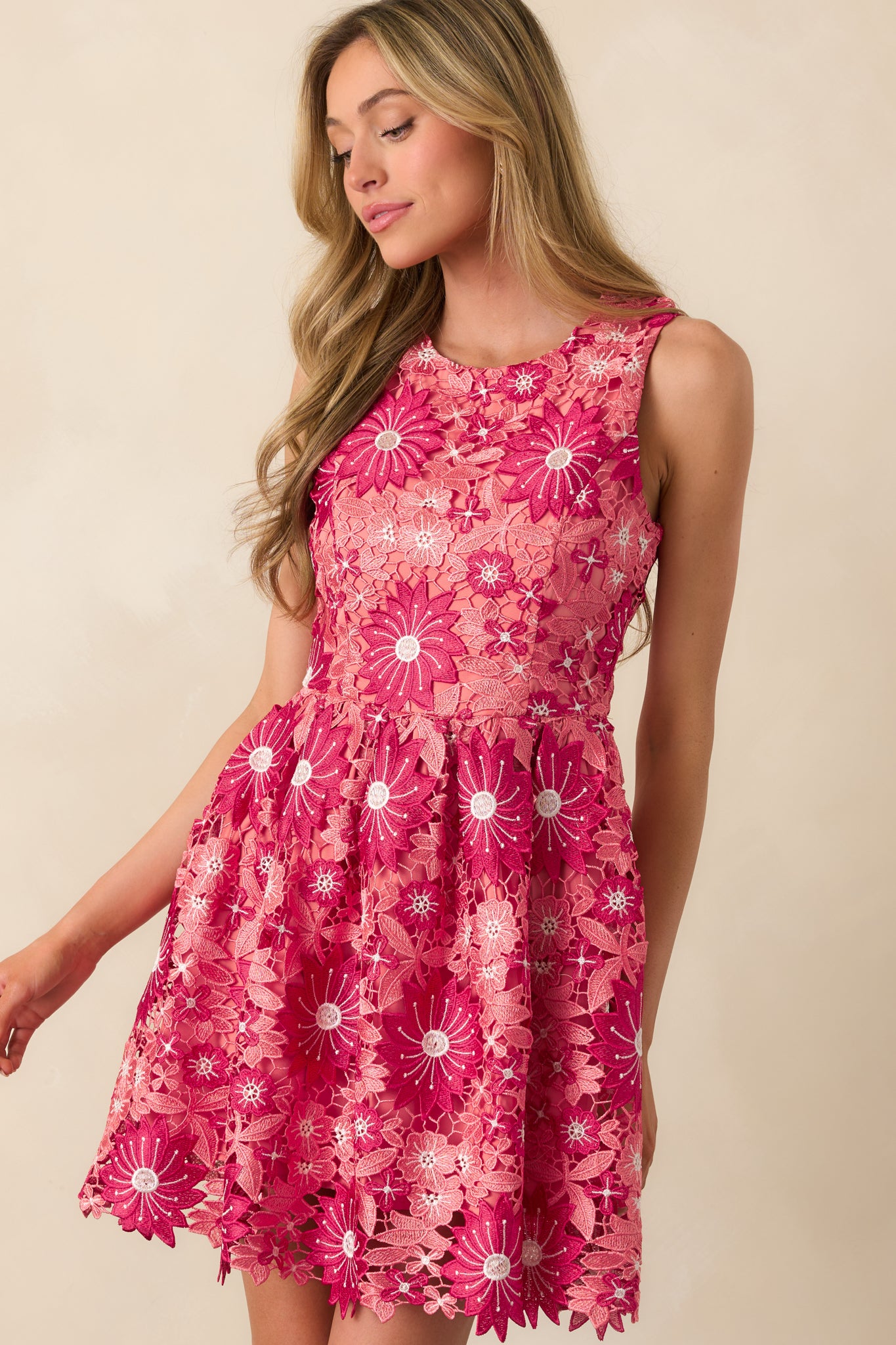 Close-up of the round neckline and sleeveless structure of the rose pink dress with floral embroidery.