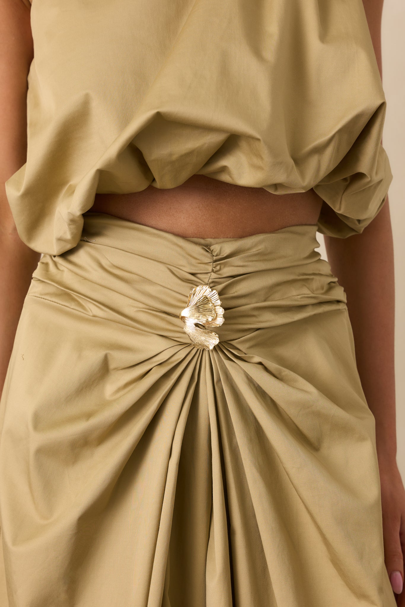 Close-up of the ruched waistband and 3D gold embellishment, showing the intricate texture and fabric detail.