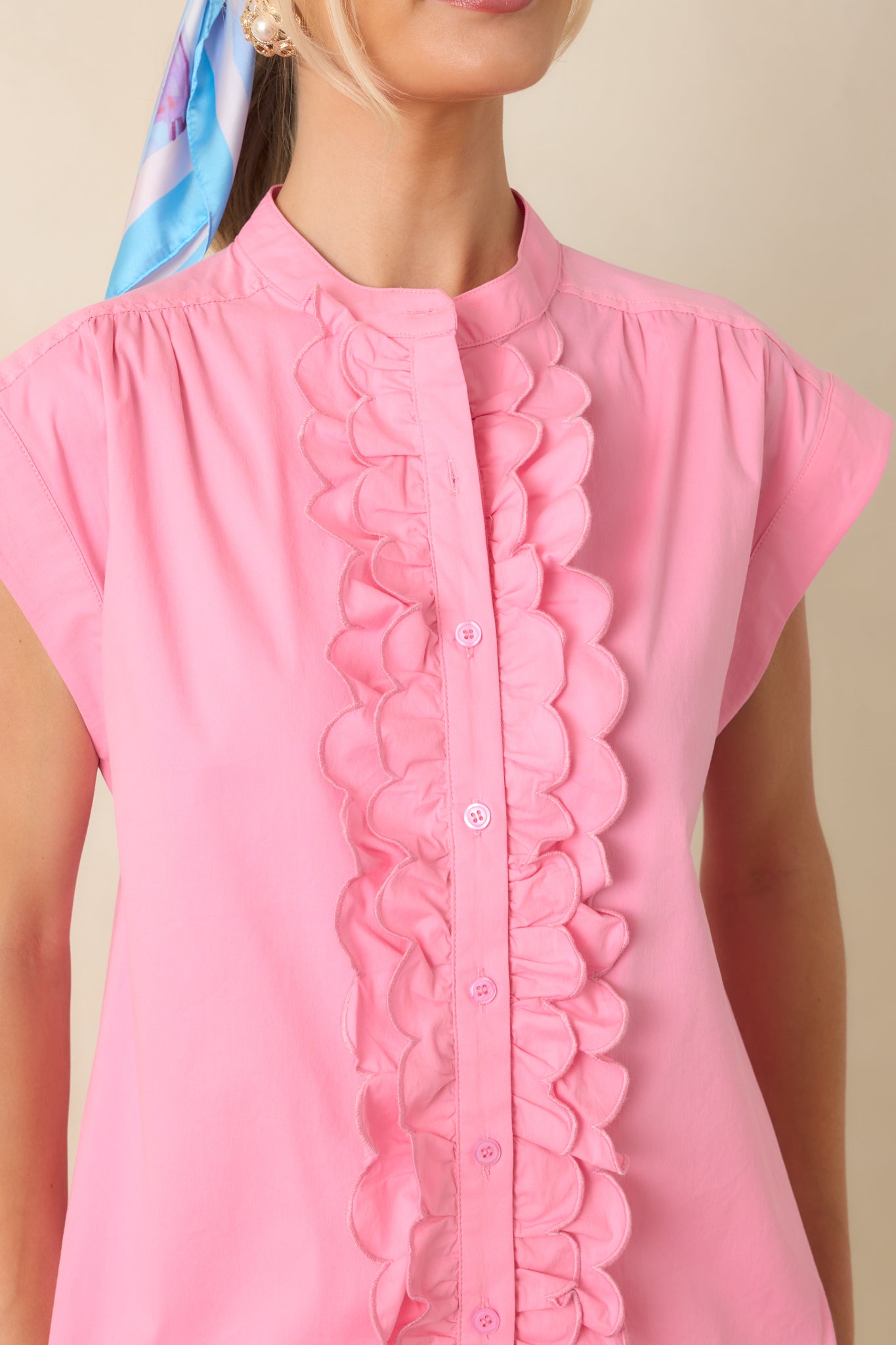 Close-up of the pink top highlighting the scalloped ruffle trim, functional buttons, and refined cotton blend fabric texture.