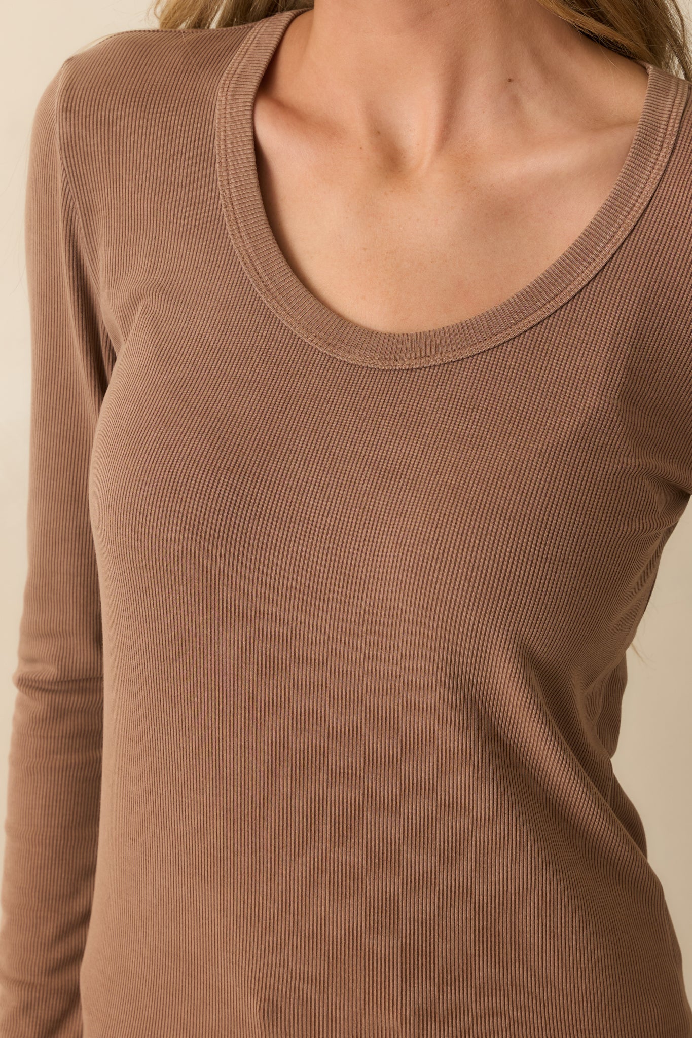 Close-up of the scoop neckline and long sleeves showing fabric texture and stitching.