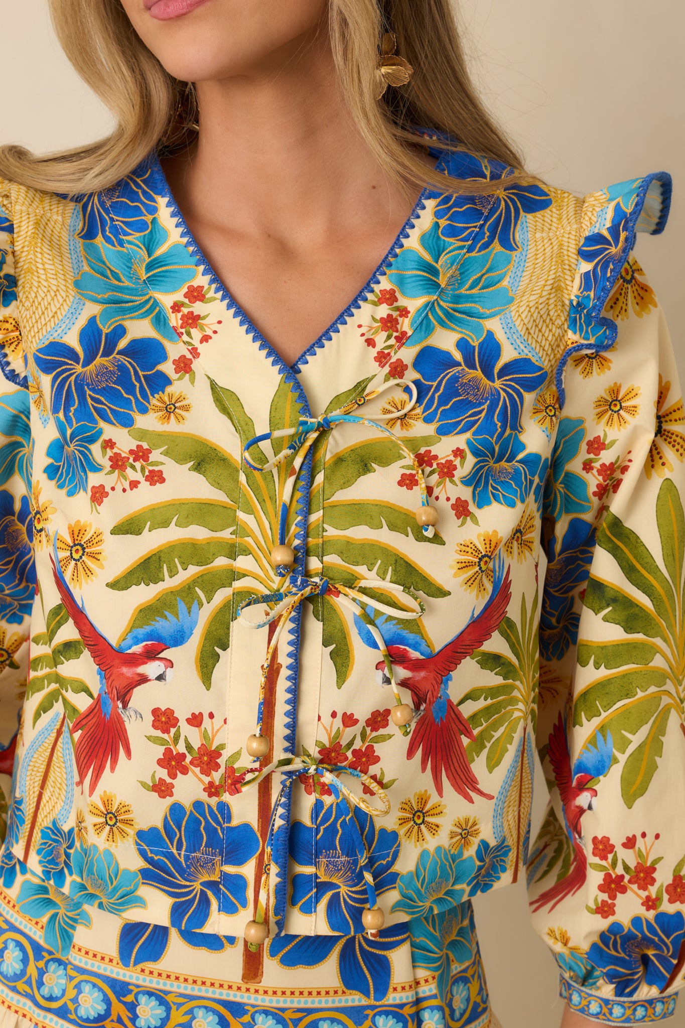 Close-up of tie-front closure with beads, ruffled shoulder, and balloon sleeve on top.
